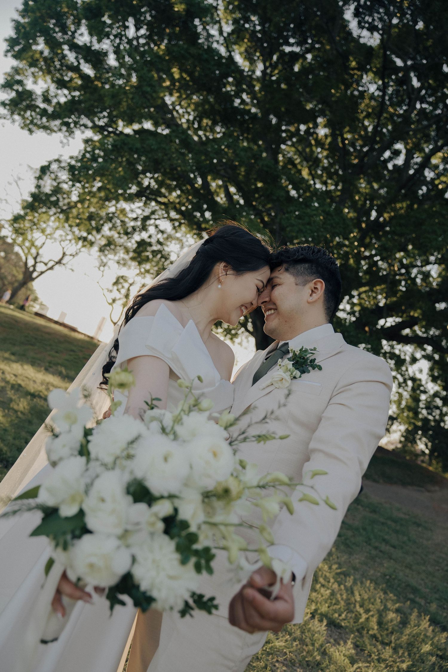 Newlyweds share an intimate moment in a garden setting with elegant white flowers.
