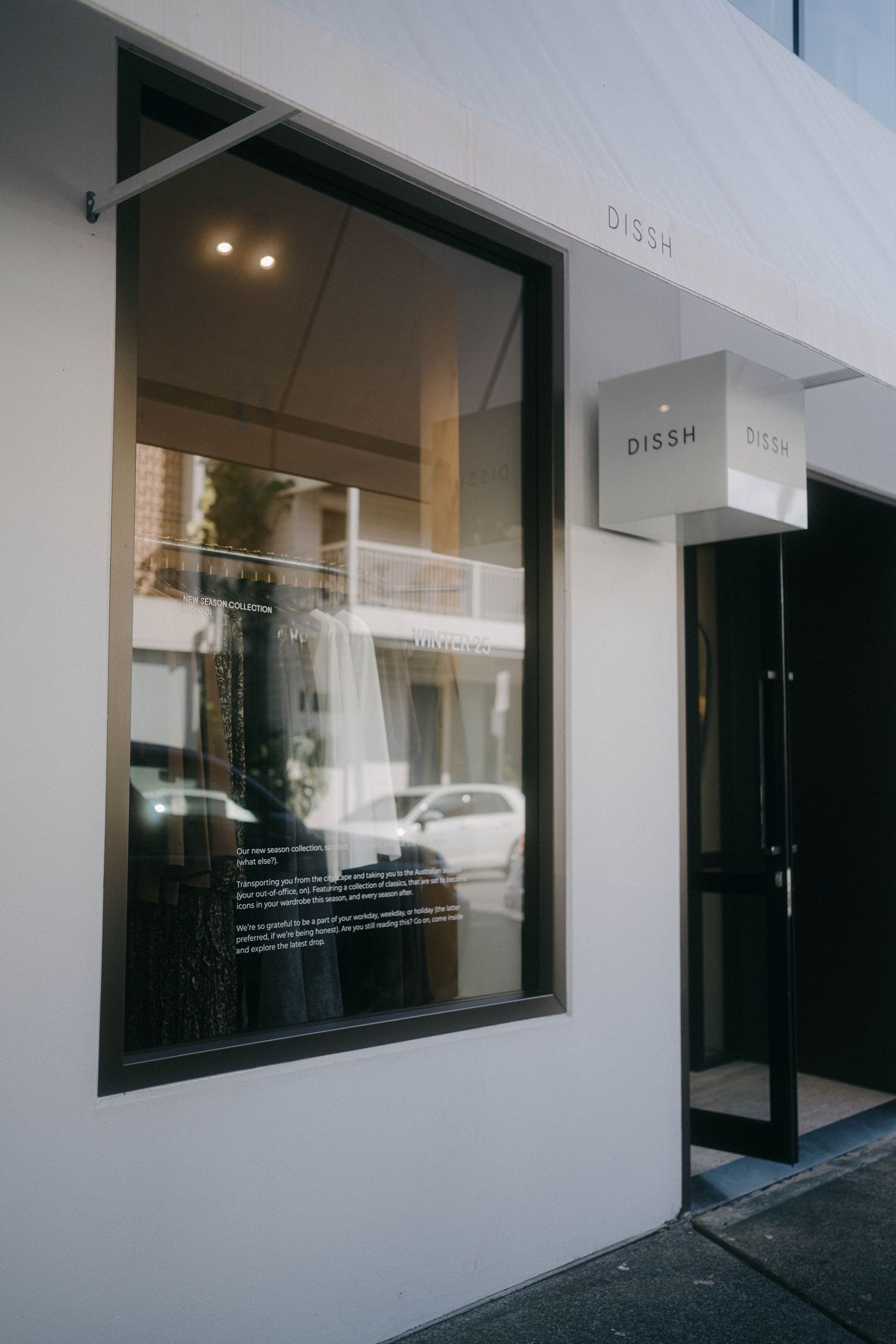 Minimalist white storefront with large glass windows and simple black trim displaying the name 'DISSH'.