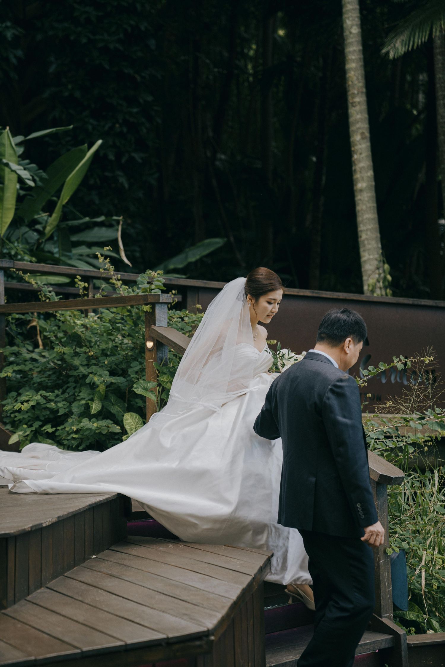 A flowing white bridal veil catches the breeze in a series of outdoor wedding photos on a wooden deck.