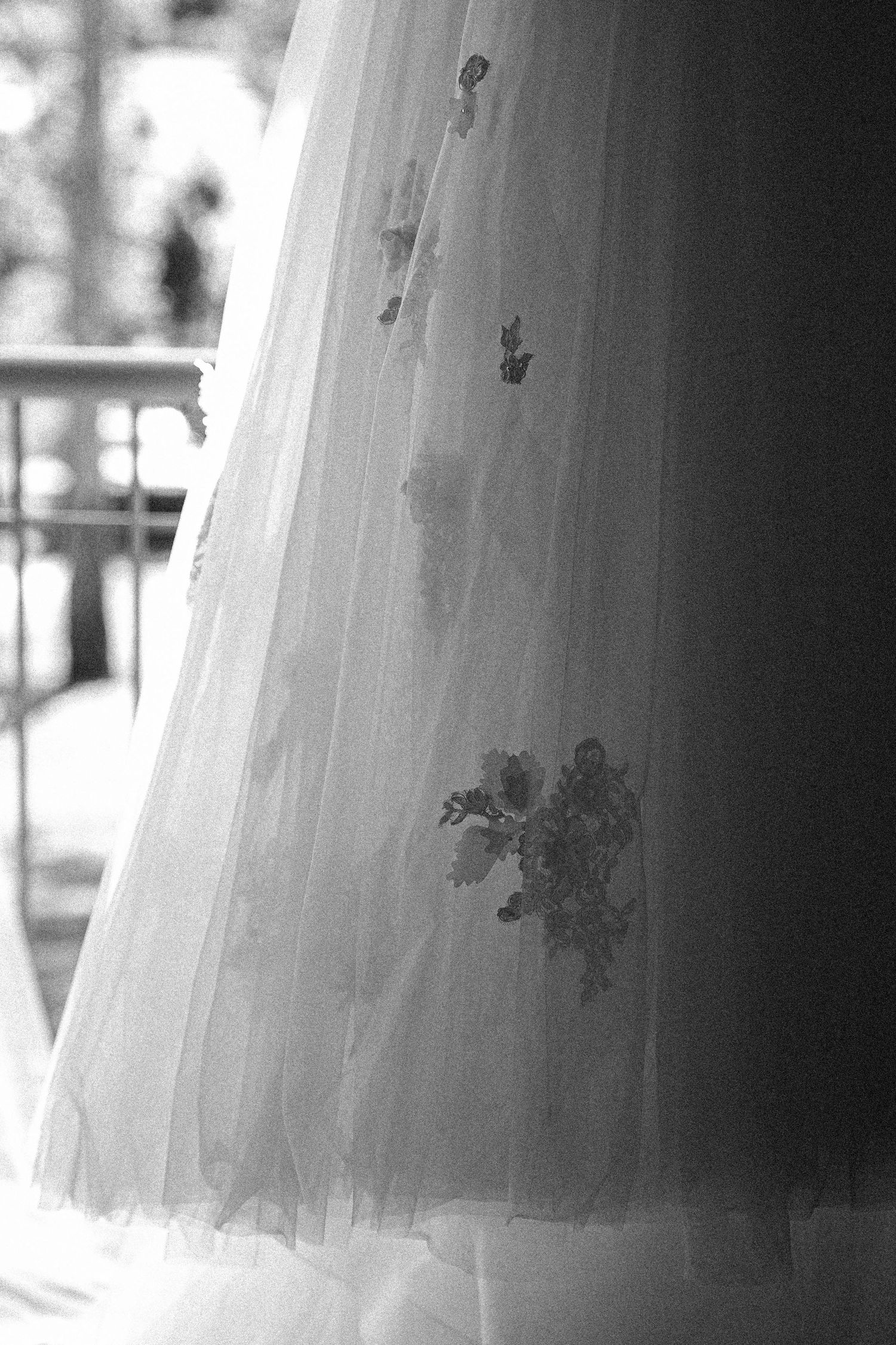 Close-up view of delicate white tulle wedding dress fabric with lace embellishments in black and white photography.