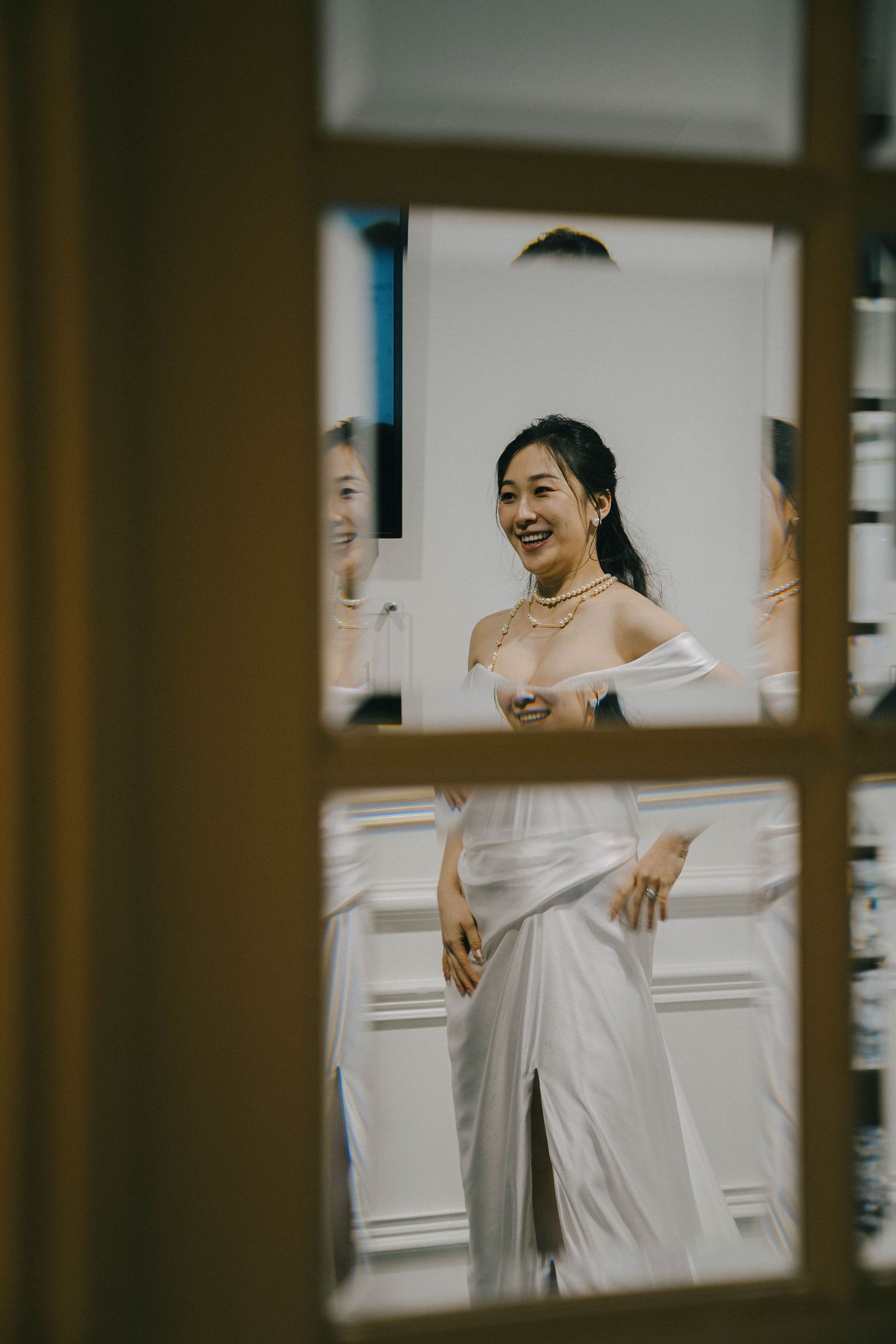 Wedding scene through window panes showing joyful moments in white attire.