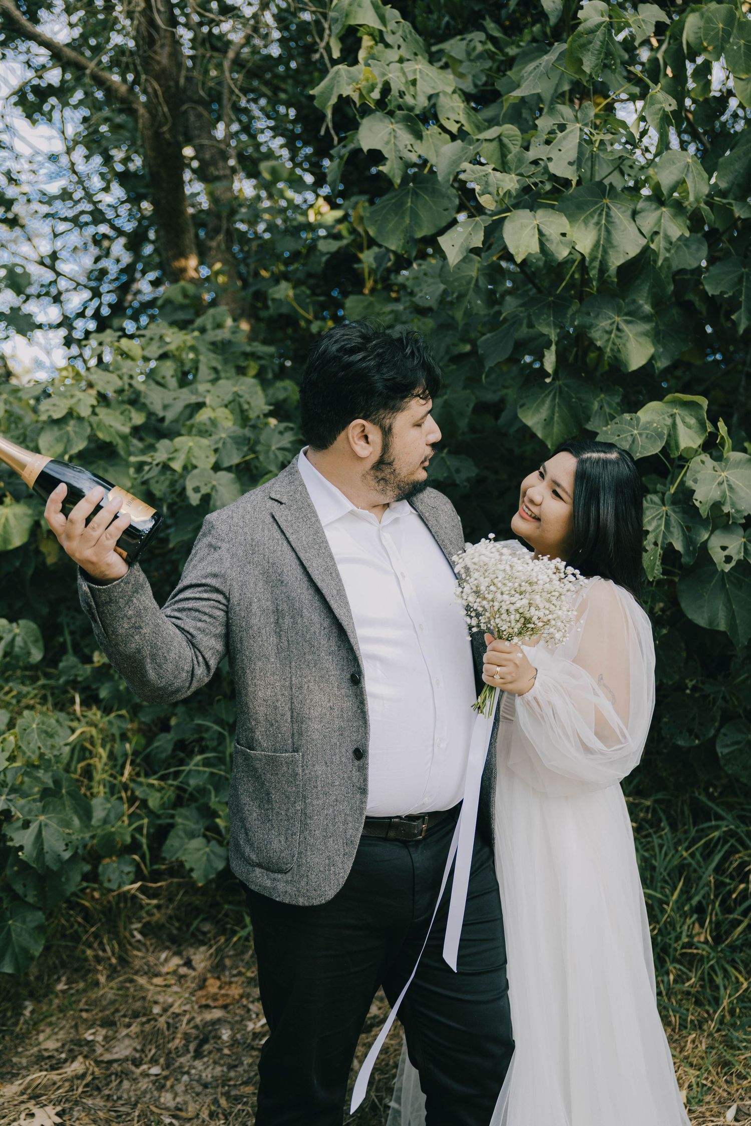 A romantic couple shares intimate moments among lush green grapevines in a vineyard setting.