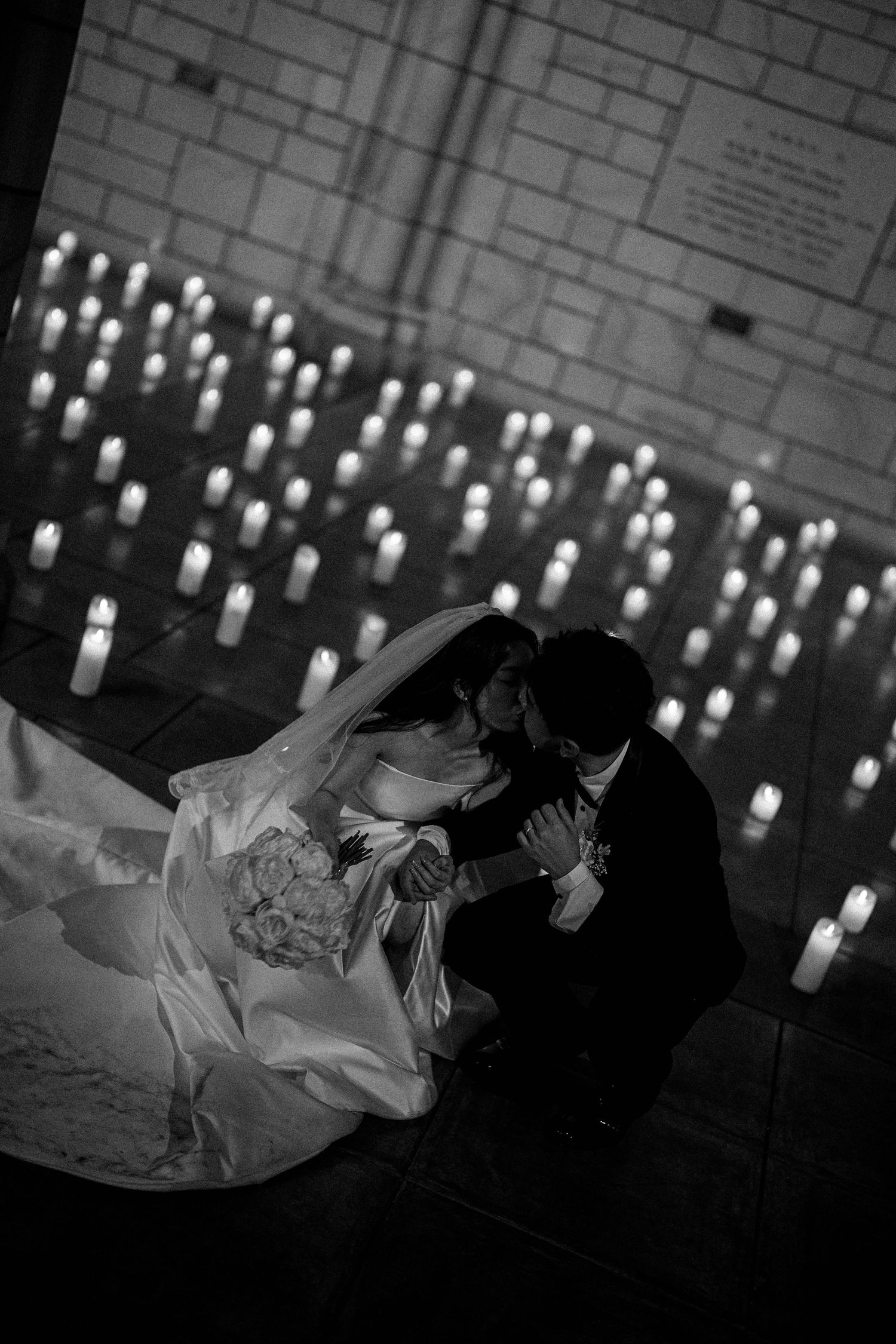 A romantic black and white photo sequence of a couple lying together surrounded by glowing candles in the background.