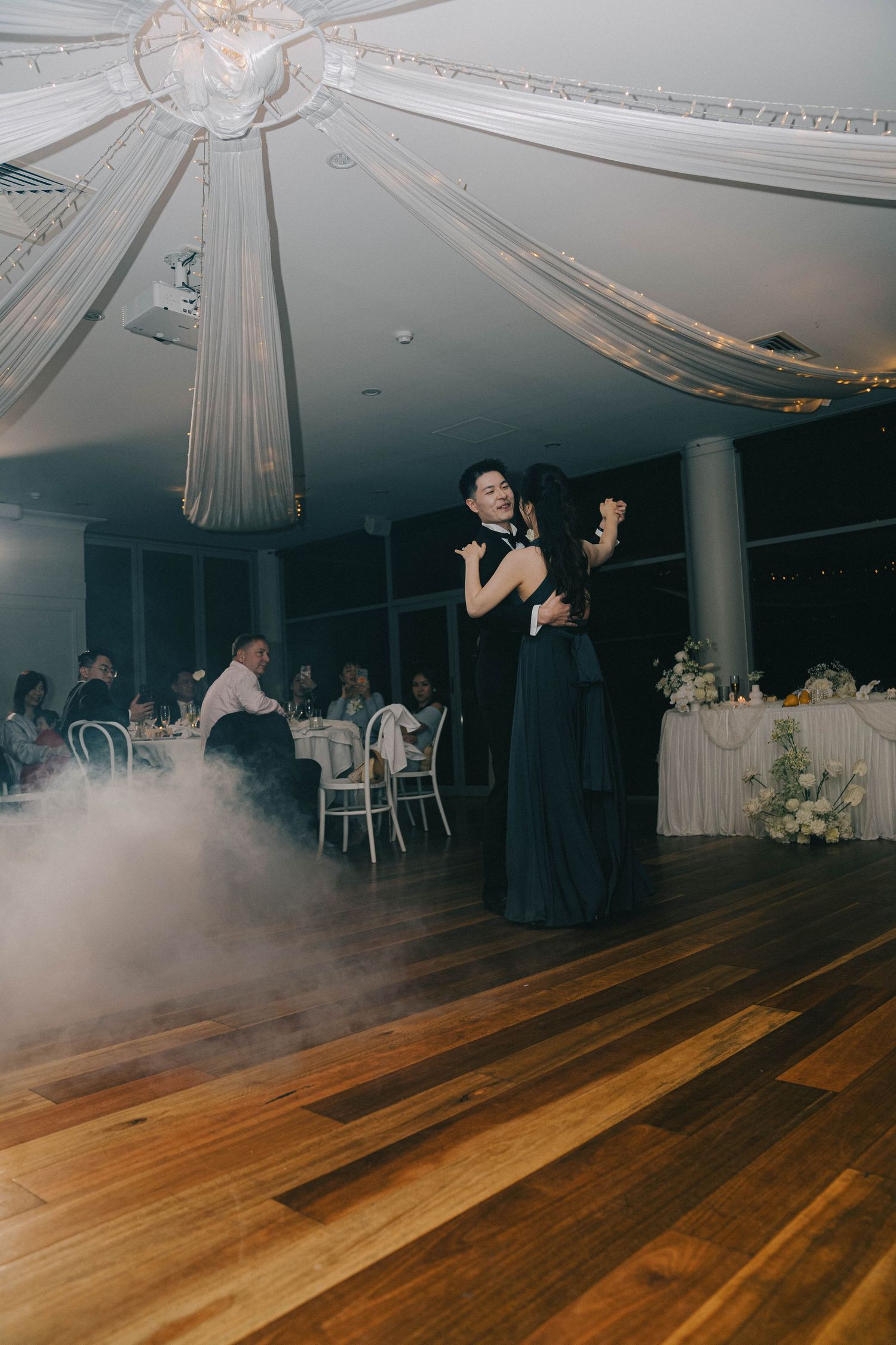 A sequence of photos showing fog or smoke effects on a wooden dance floor at an elegant indoor wedding reception venue.