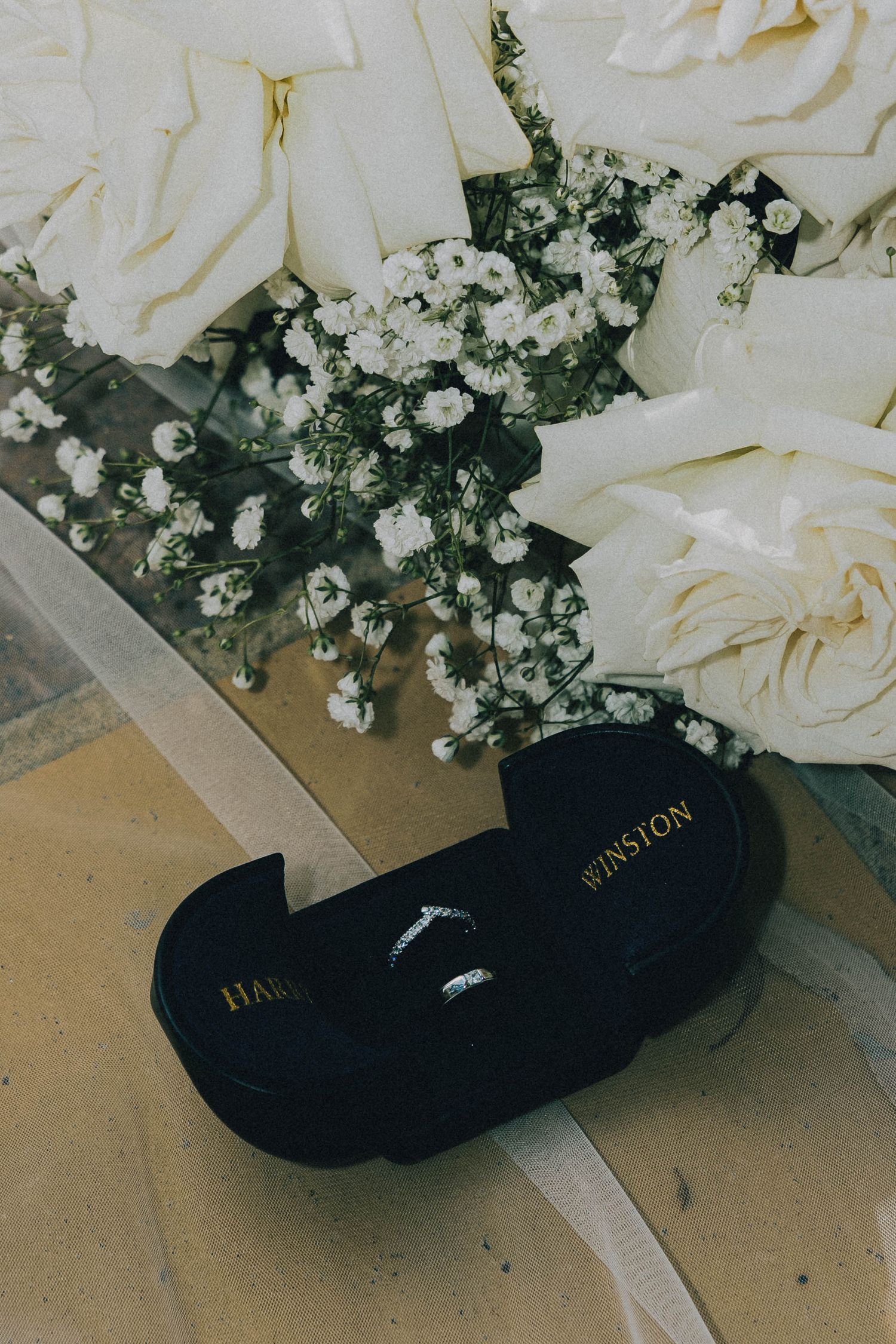 White roses and baby's breath floral arrangement with a black shoe peeking out from underneath.
