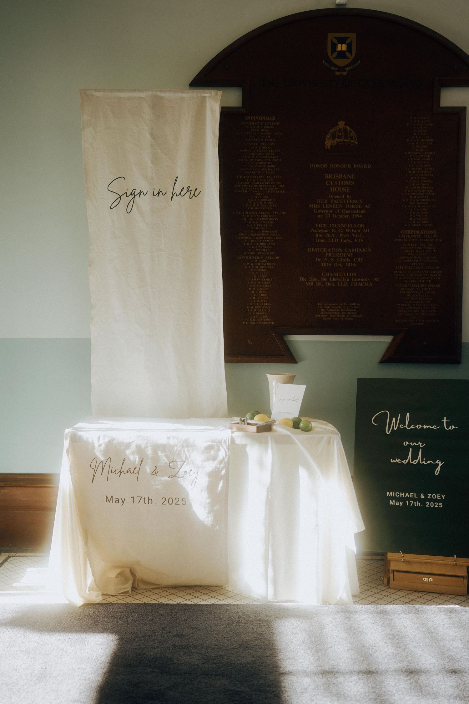 Wedding ceremony signage boards in rustic tones against dark walls with natural lighting.
