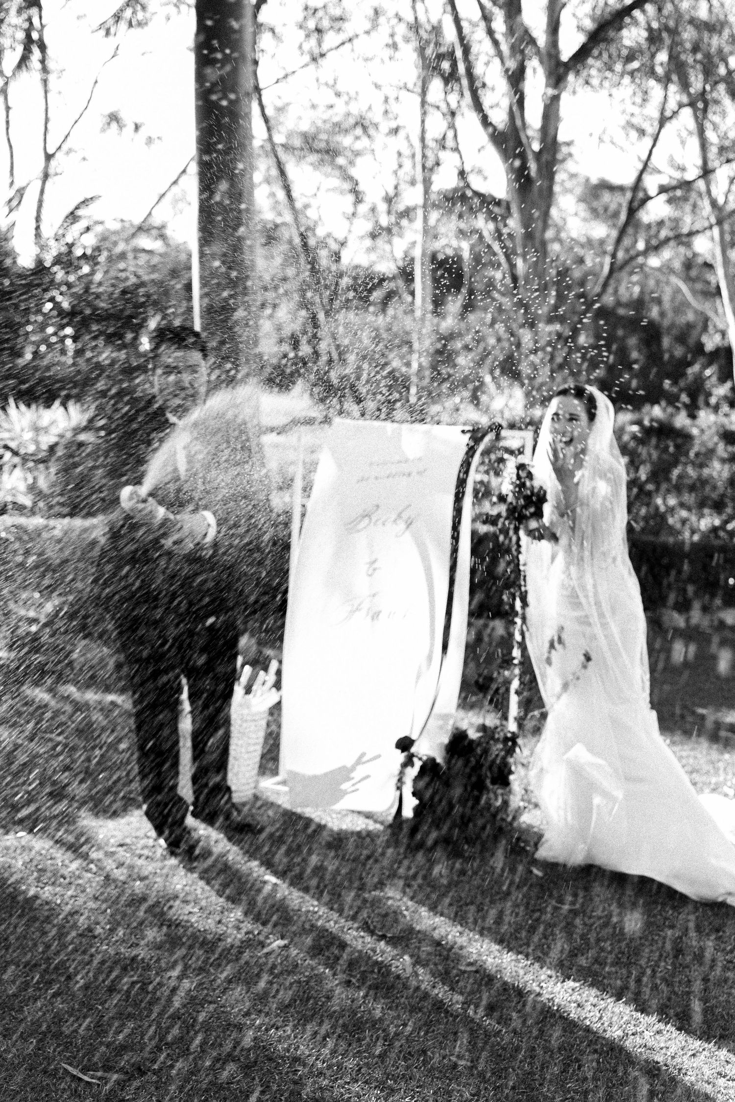 Black and white photograph showing white laundry hanging on clotheslines outdoors against a backdrop of trees.