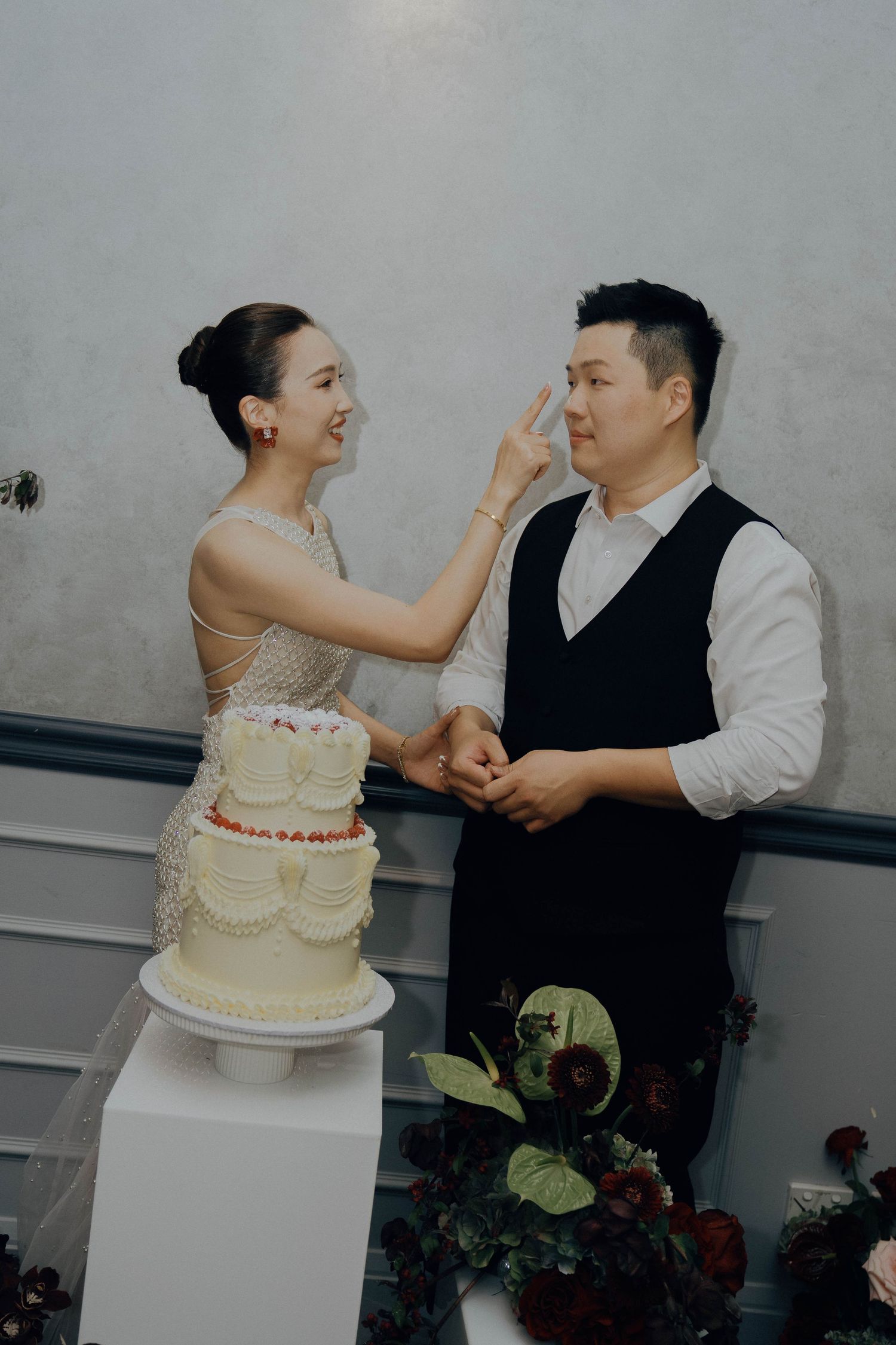 A couple playfully feeds each other wedding cake during their reception celebration.