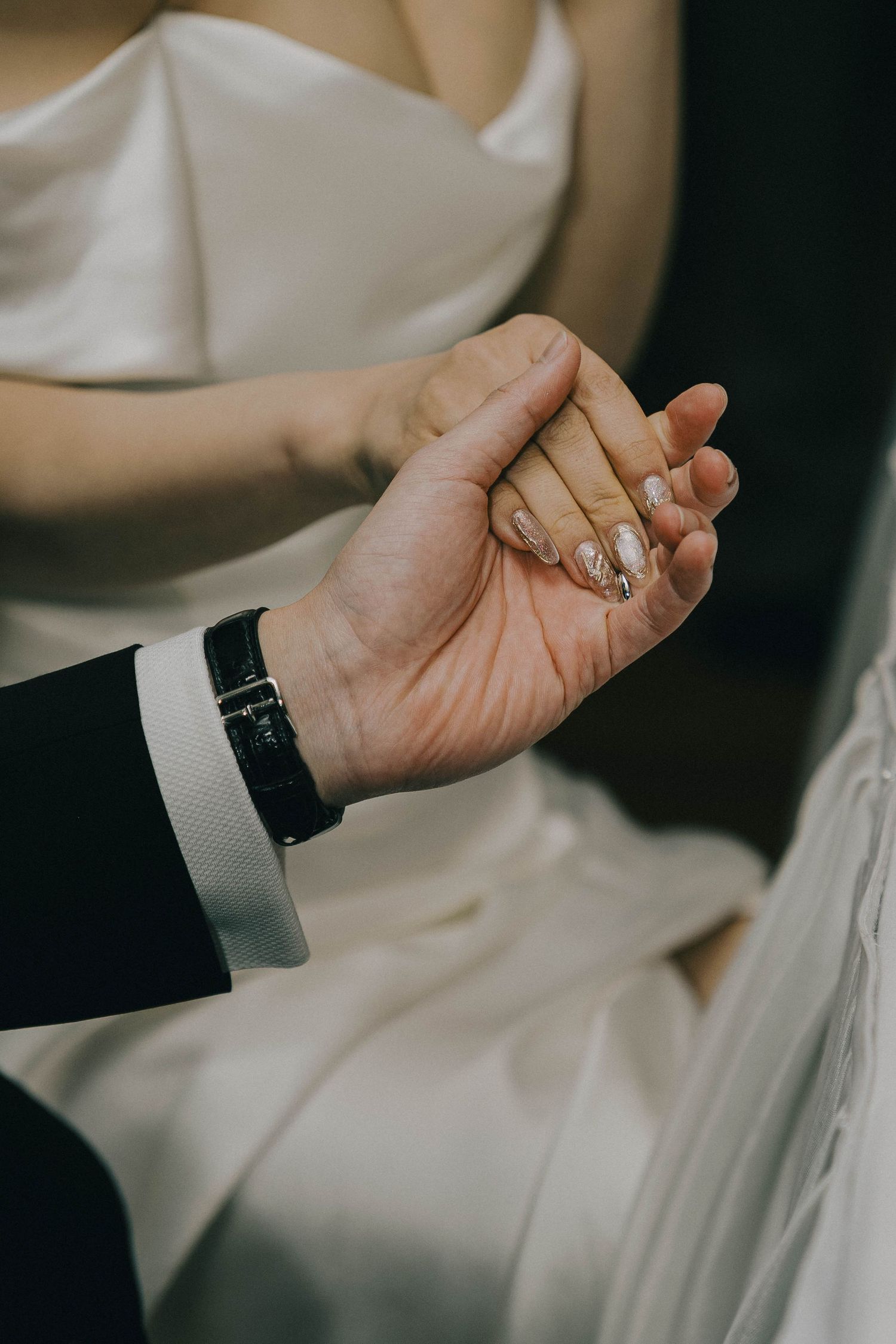 Close-up shot of hands adjusting white dress shirt cuffs with cufflinks during formal dressing preparation.