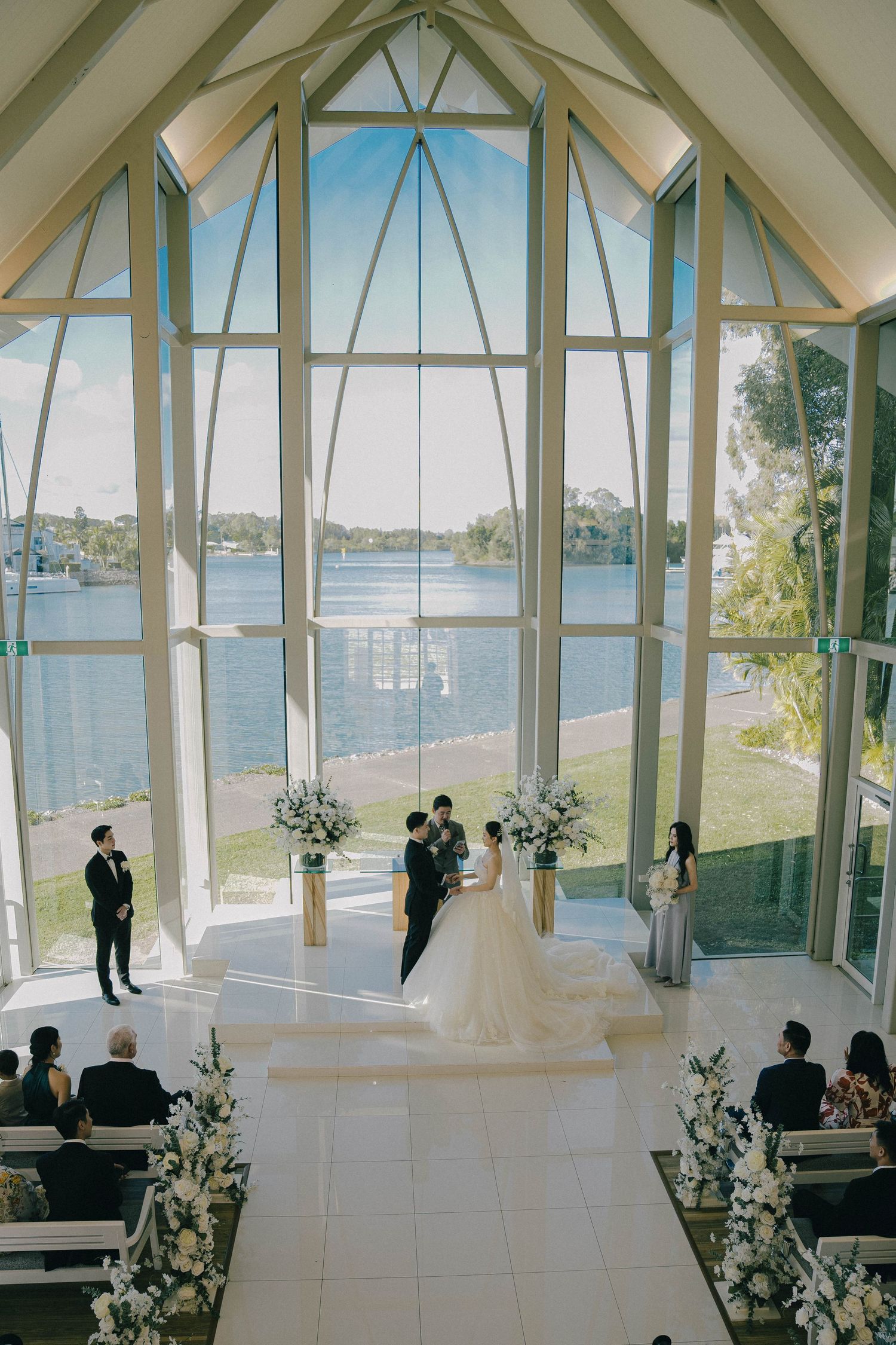 Panoramic view of a modern waterfront chapel with floor-to-ceiling windows overlooking a serene lake.