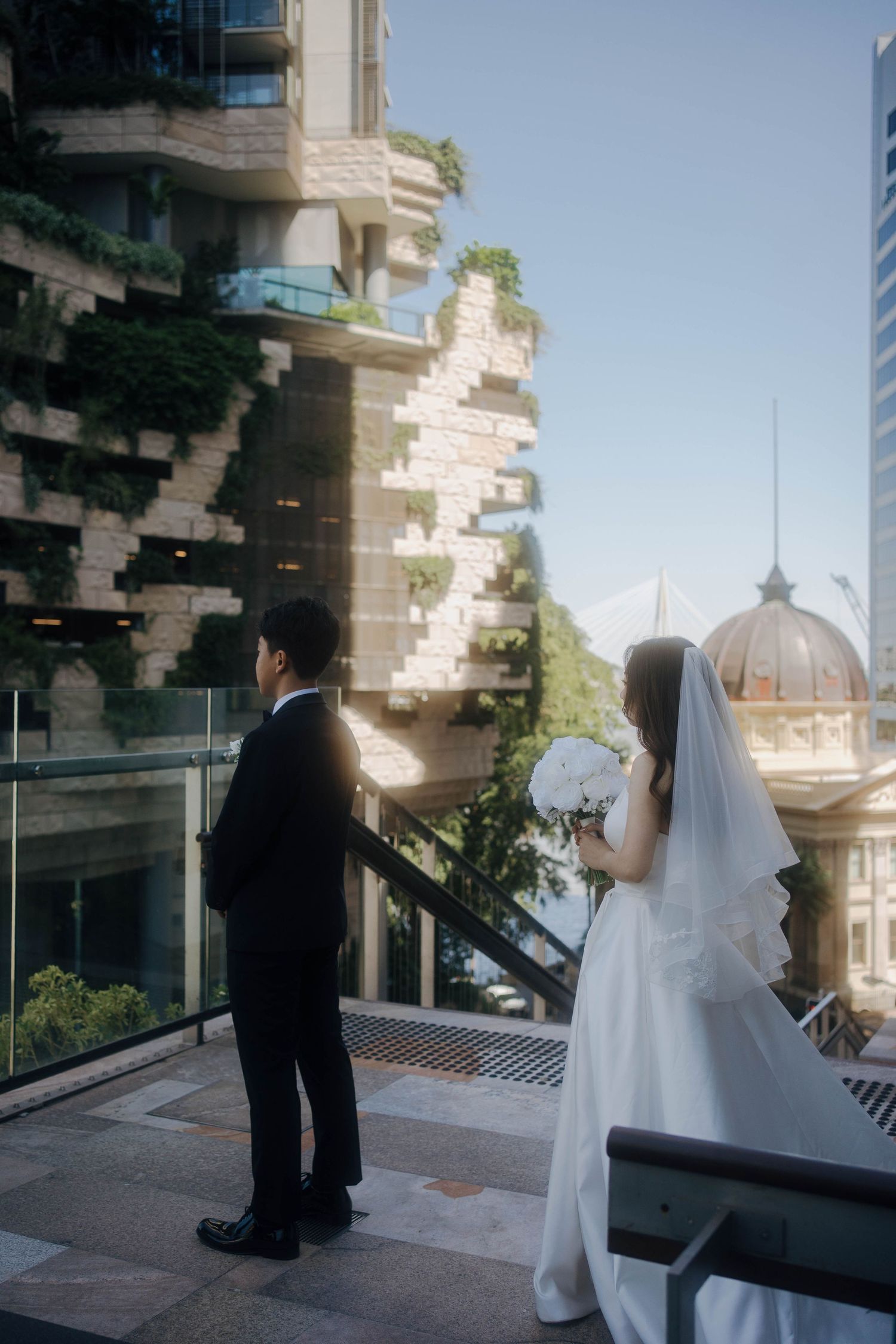 Wedding couple on a modern architectural balcony with city skyline views.