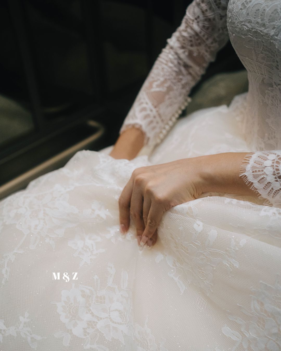 Delicate lace sleeve detail of a white wedding dress with intricate embroidery and soft tulle fabric.