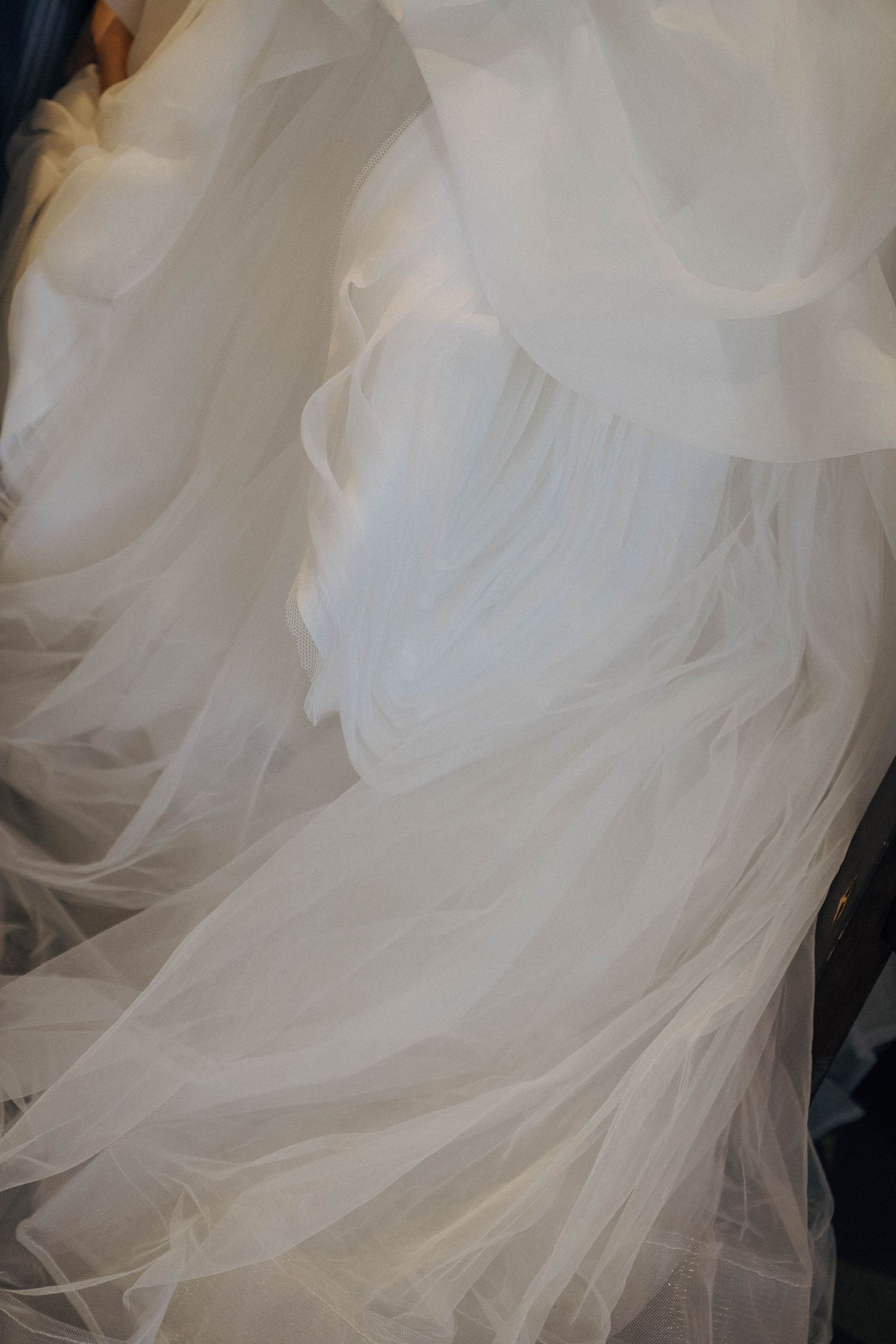 Close-up view of flowing white tulle fabric layers creating ethereal texture and movement in wedding dress details.