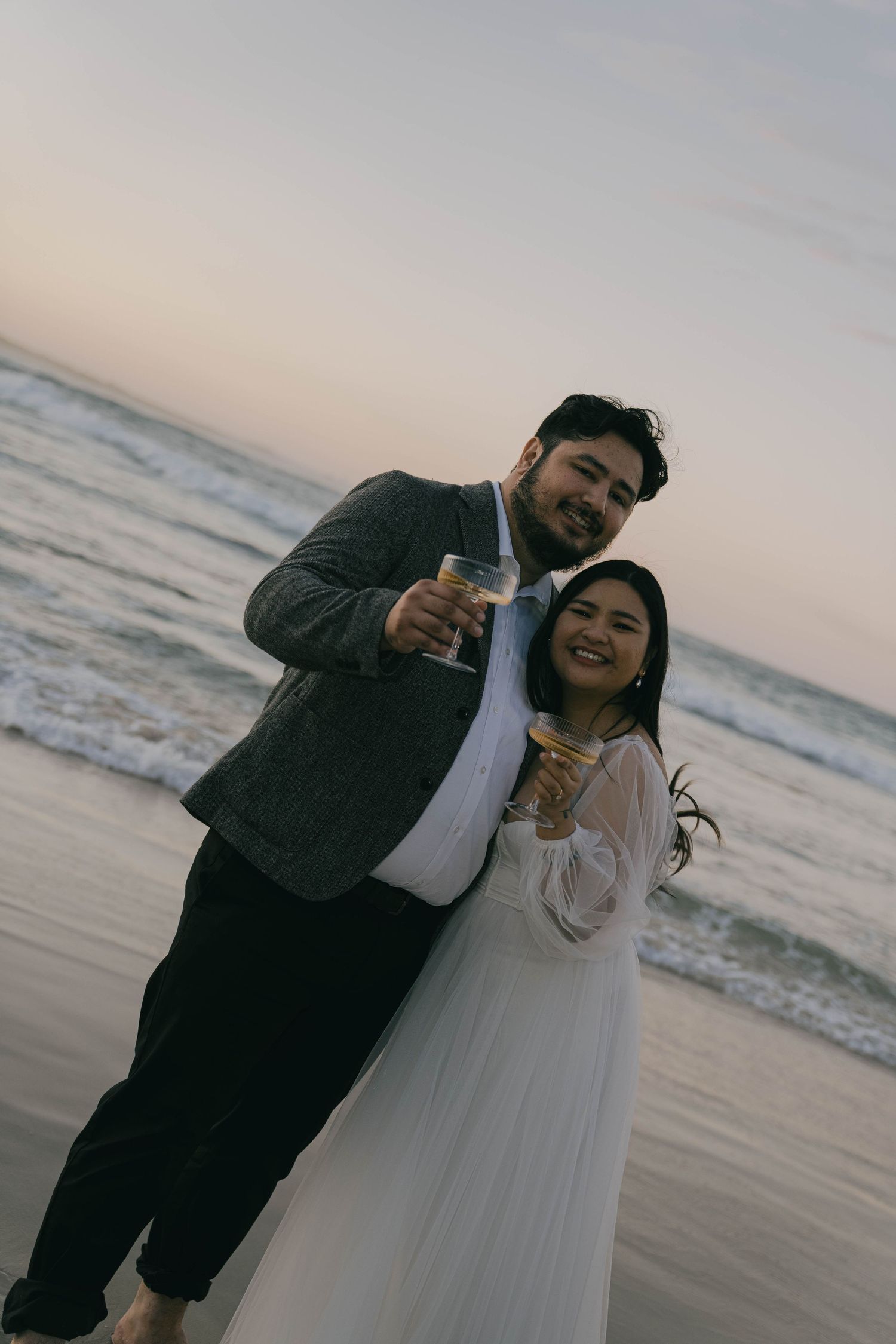 A couple celebrates on a beach at sunset with champagne bottles and romantic poses in a series of candid moments.