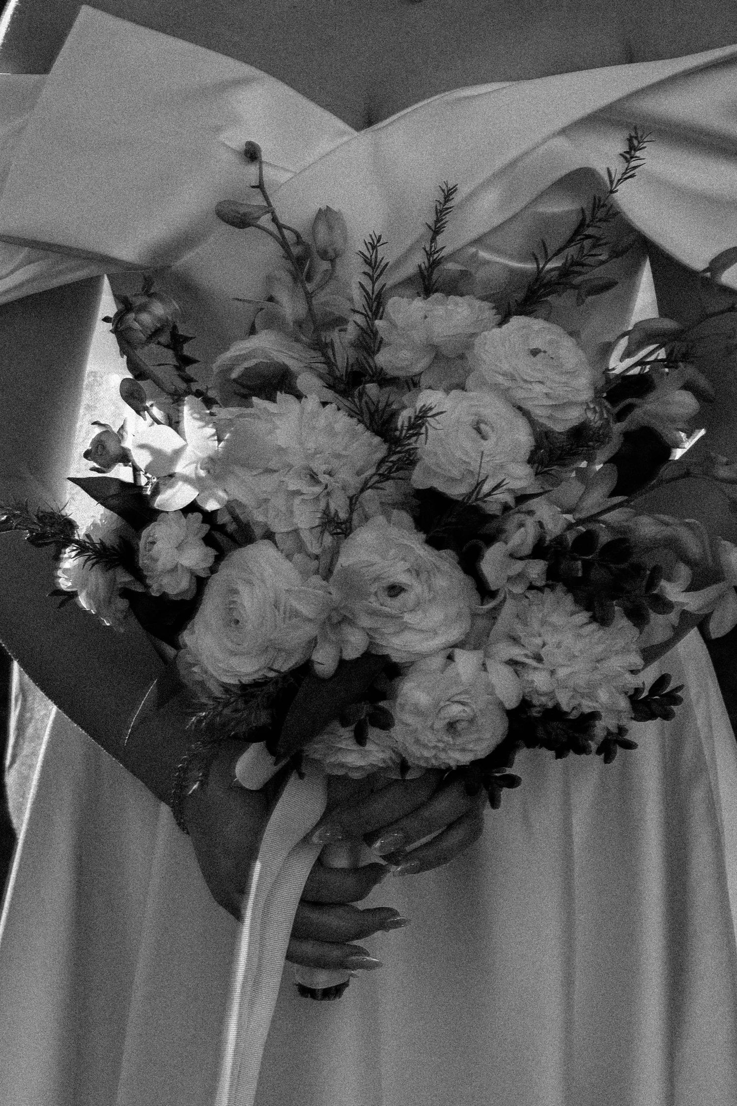 Black and white photograph of an elegant floral wedding arch decoration with white roses and greenery.