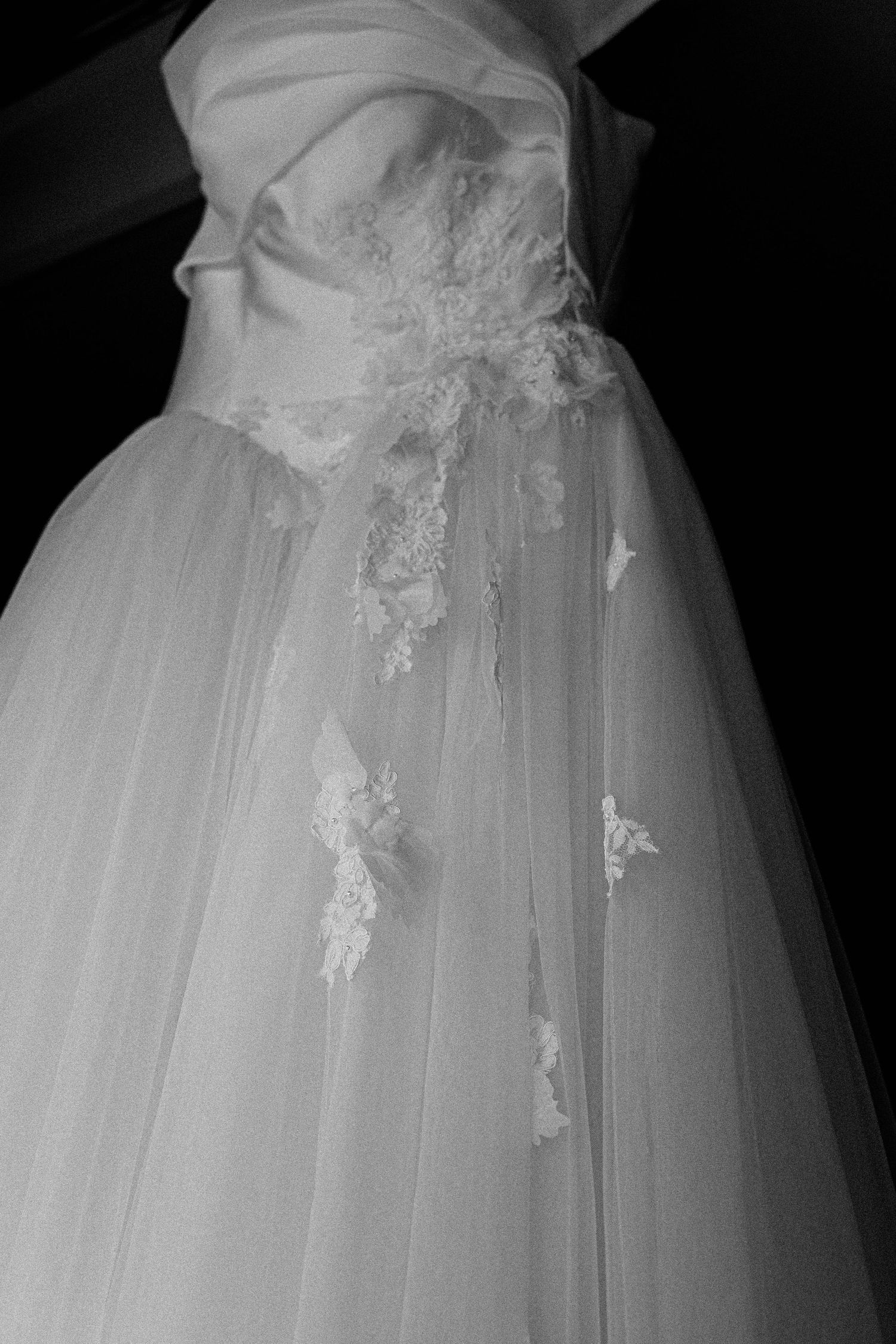 Close-up details of delicate white lace and tulle embellishments on a wedding gown skirt.