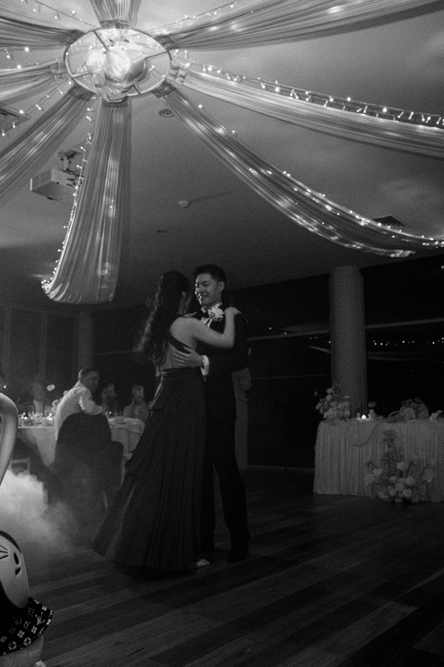 Black and white photos show couples dancing at a wedding reception under a tent with string lights and decor.