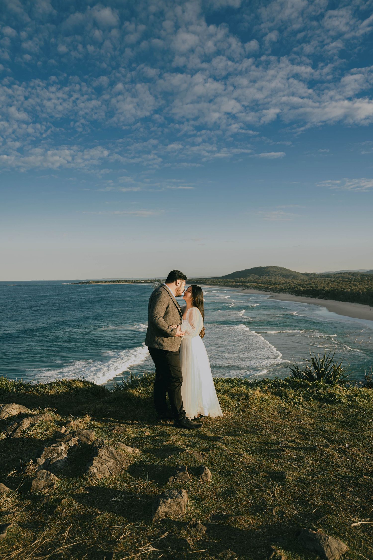 Scenic coastal landscape with sweeping ocean views and dramatic cliffs under a cloudy blue sky at sunset.