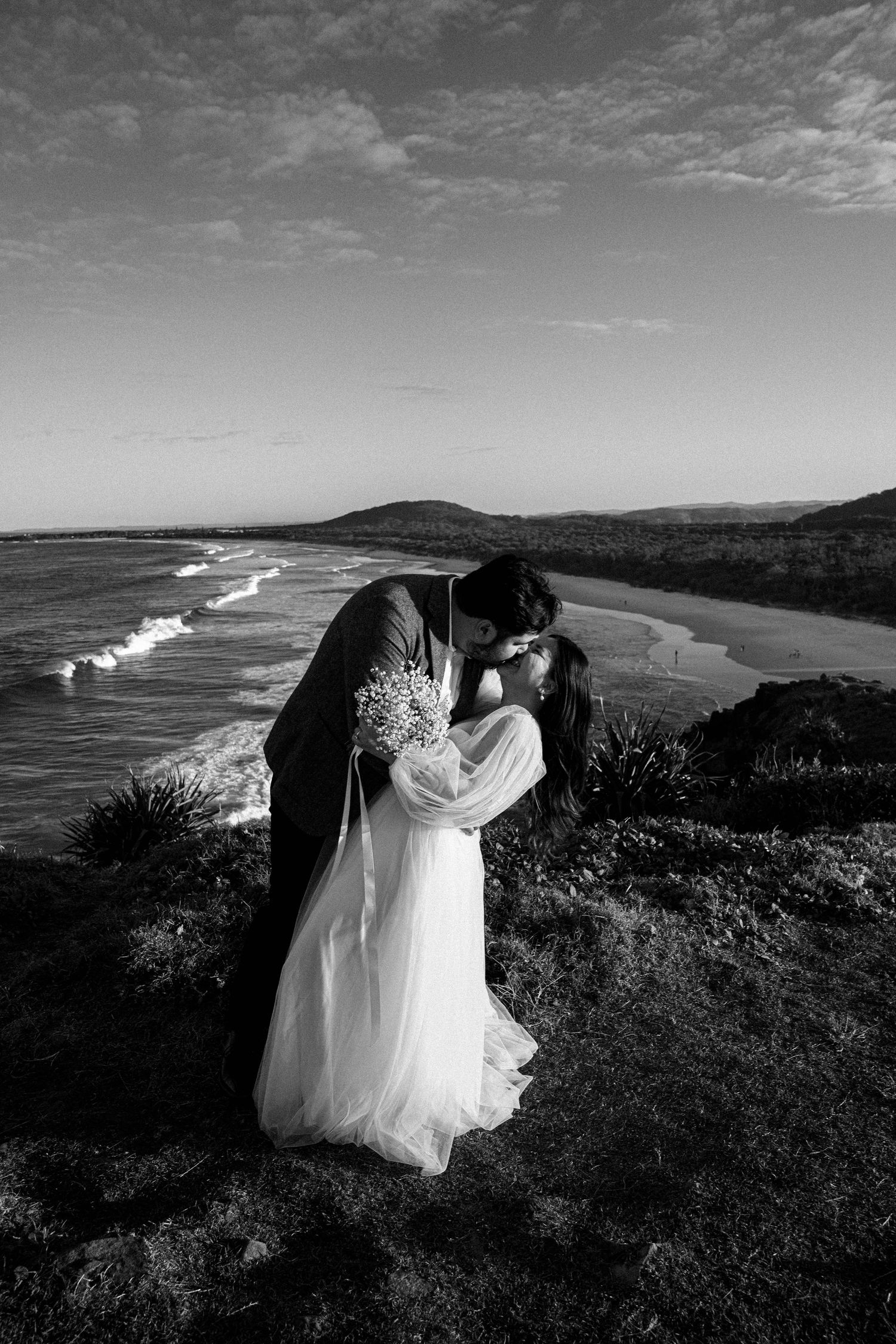 Black and white coastal wedding photography series showing romantic moments against dramatic ocean cliffs and waves.
