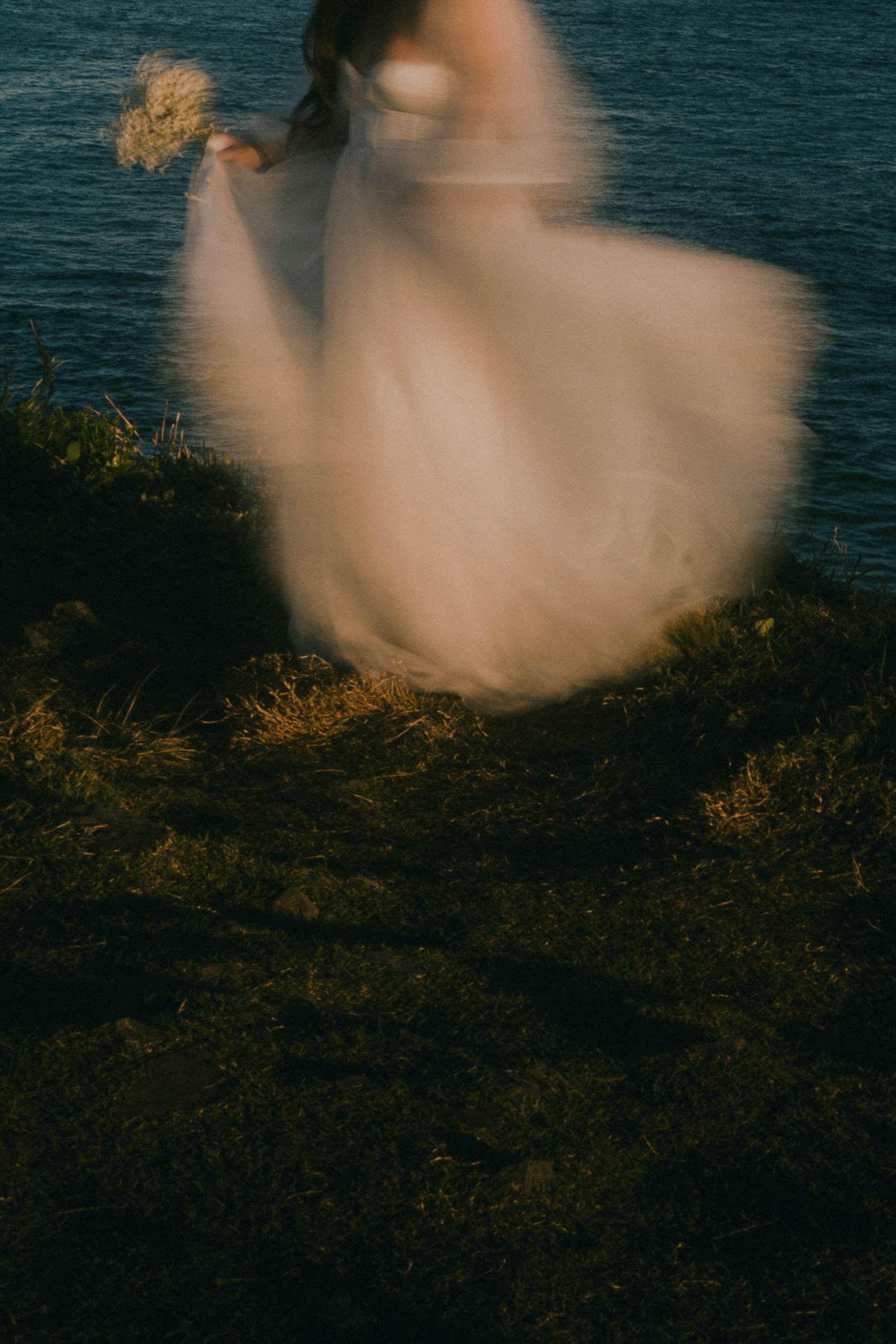 A series of ethereal motion blur photos showing a white flowing dress against a dark moody ocean background.