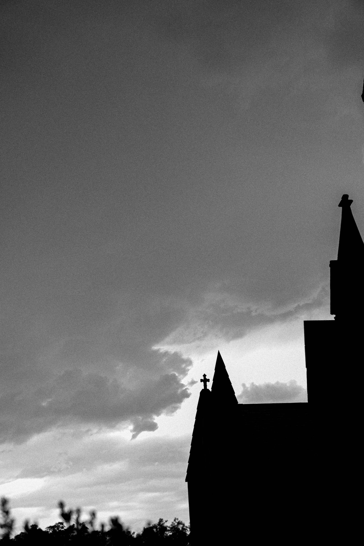 Dark silhouettes of buildings against a dramatic cloudy sky at dusk create a moody urban landscape.