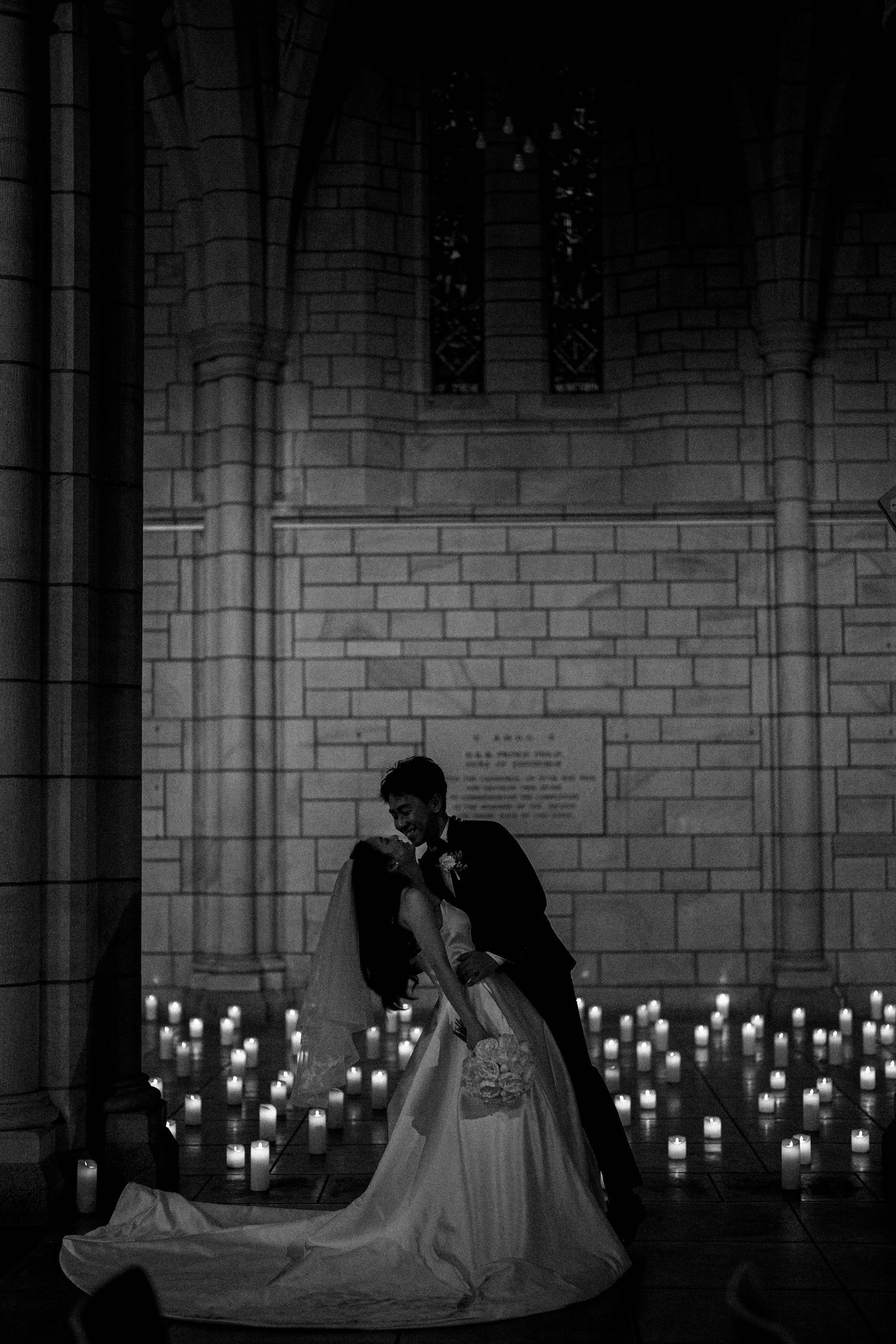 Romantic silhouettes of newlyweds kissing in a church with glowing candles creating an intimate atmosphere.