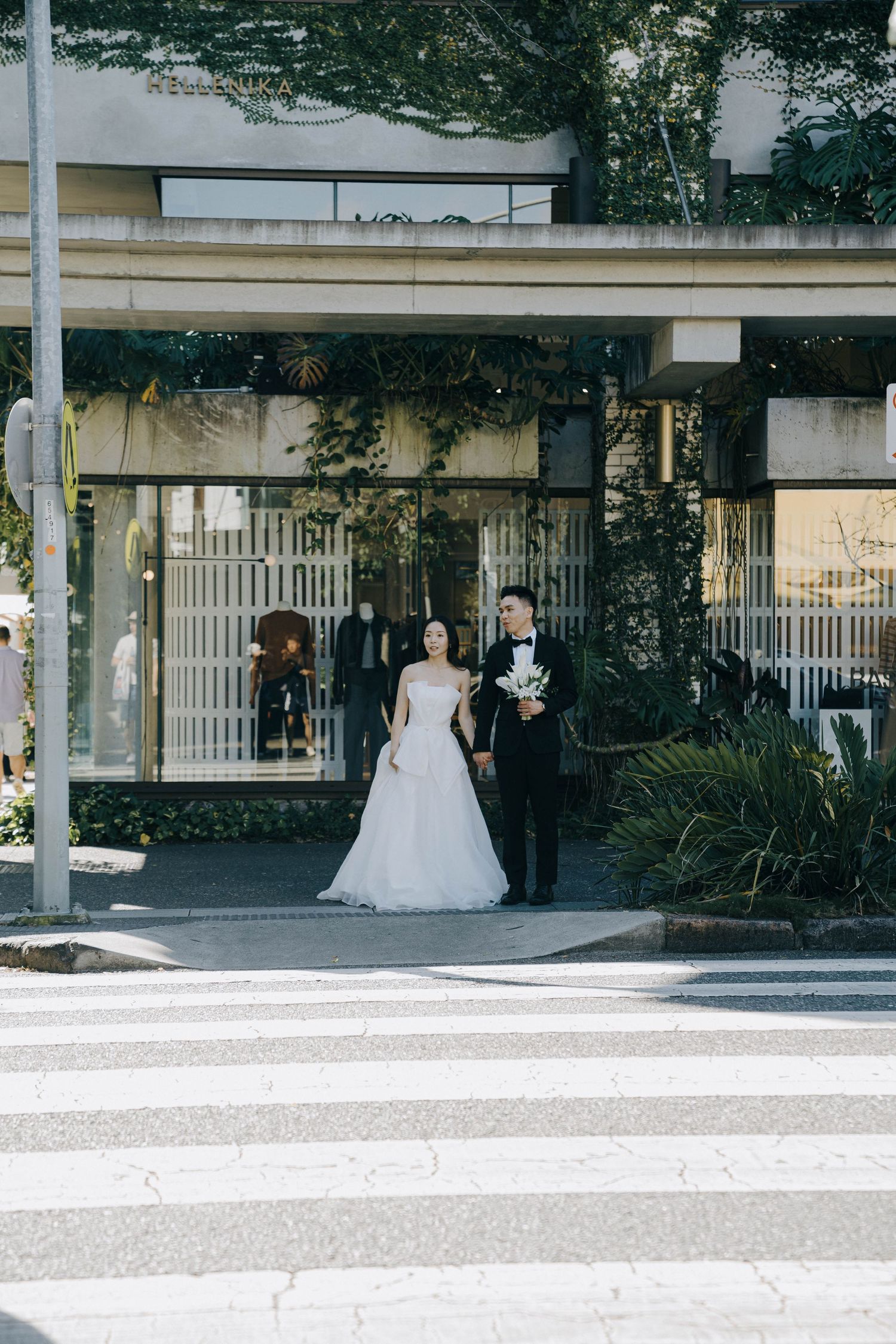 A bride in a white wedding gown and groom walk together through an outdoor courtyard on their wedding day.