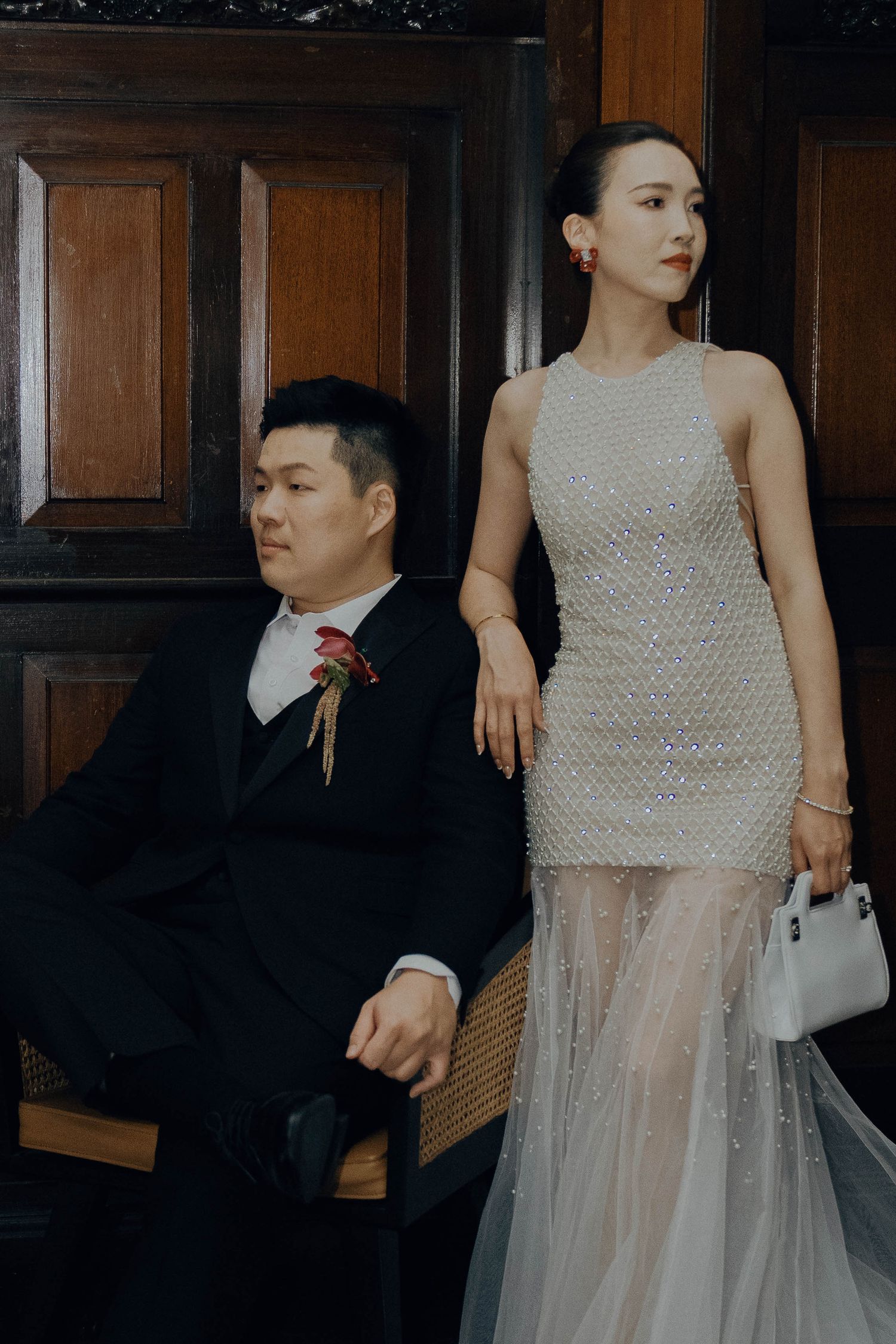 A couple in formal attire poses together, with the bride wearing a textured sleeveless top and flowing tulle skirt.