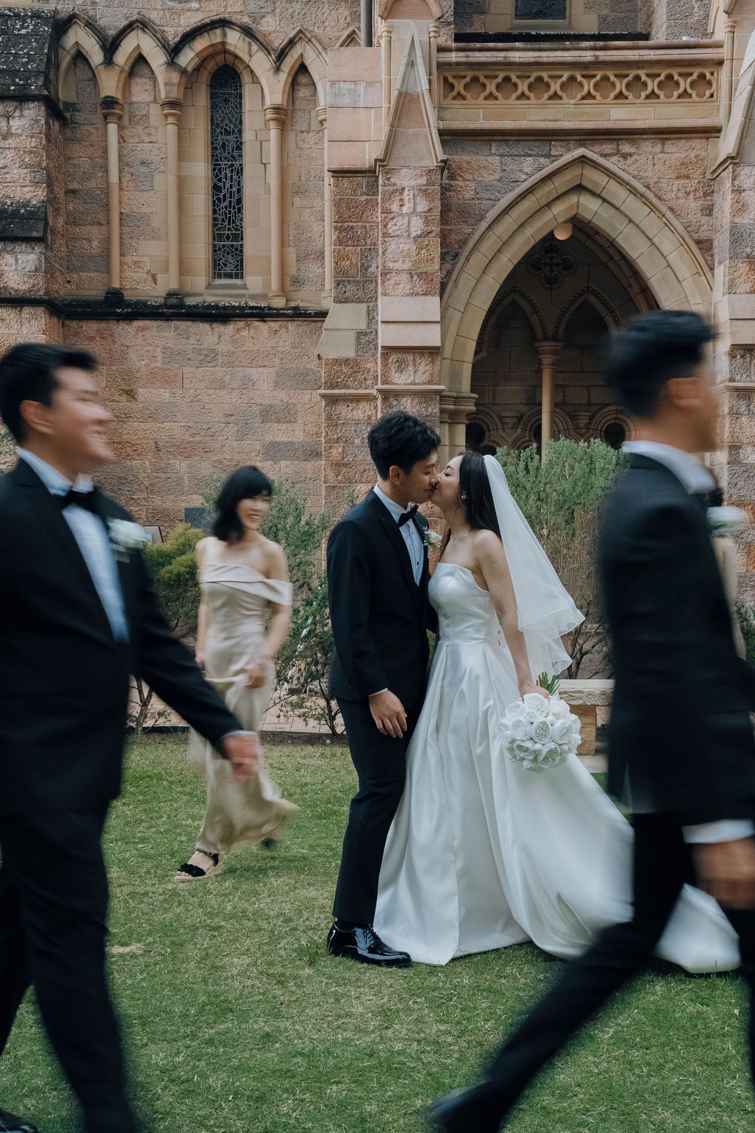 A sequence of motion shots showing a bride and groom running playfully across a church lawn.