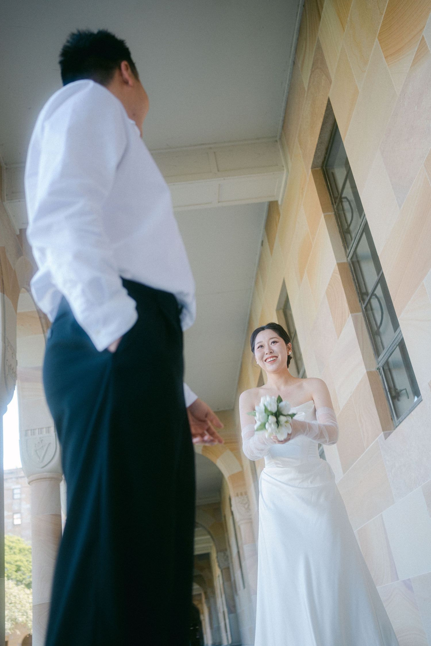 A couple shares a romantic moment in elegant wedding attire beneath a columned portico at their wedding ceremony.