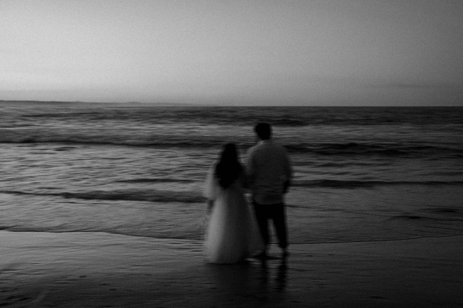 A series of black and white photographs showing silhouettes walking along a misty beach at sunset.