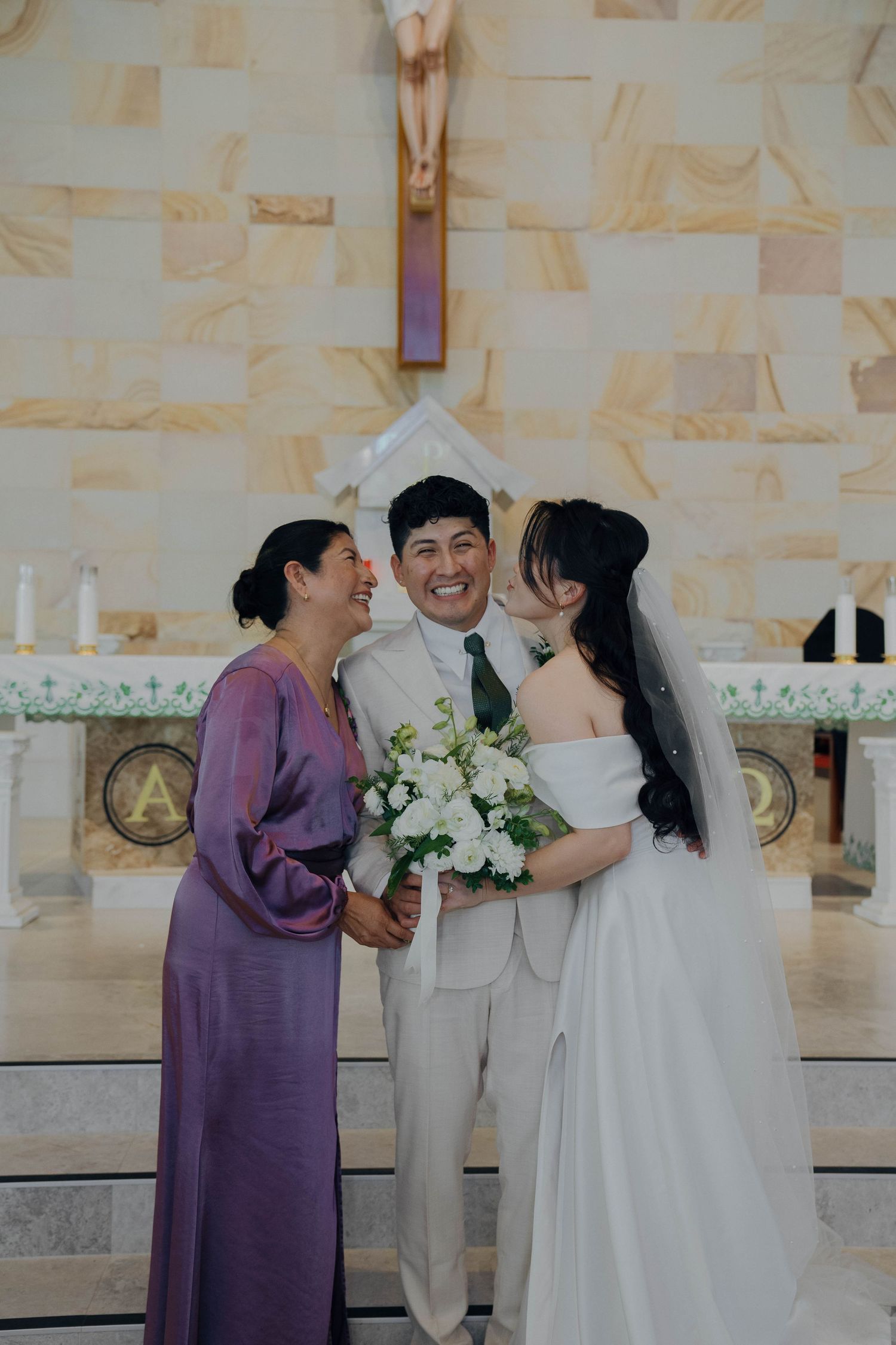 A wedding ceremony series showing moments between the couple and guests in purple and white attire at a light stone venue.
