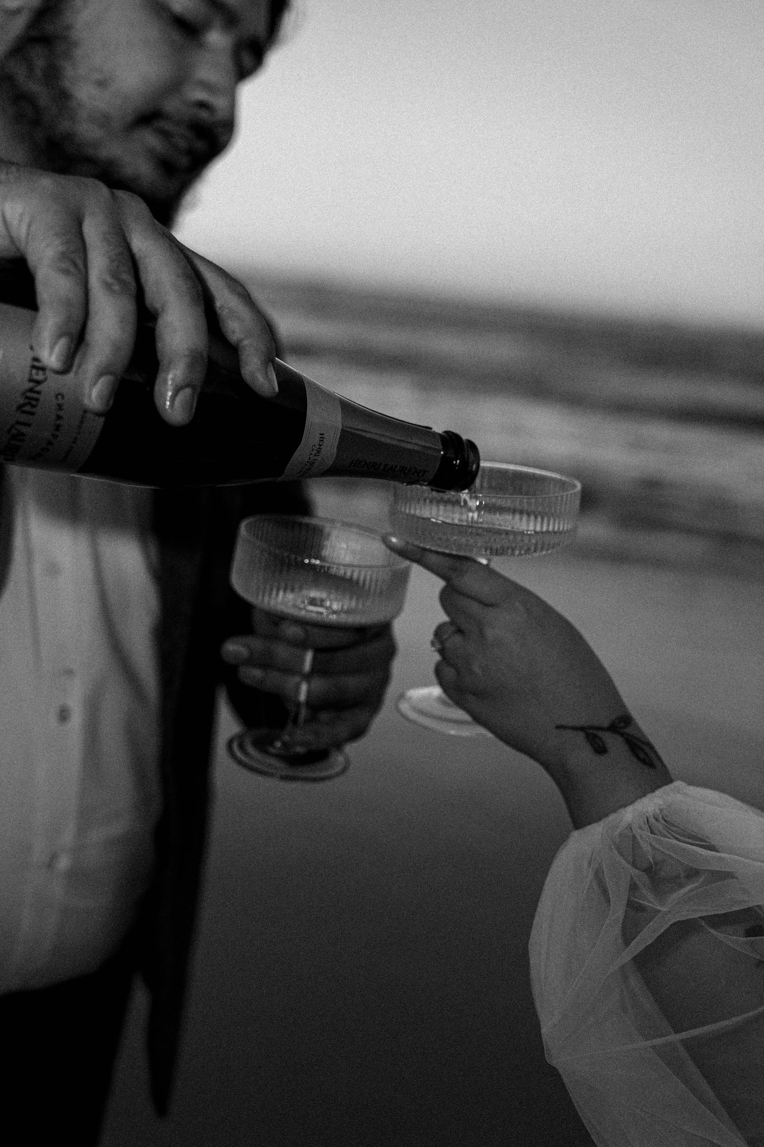 Medical professional wearing protective gear draws liquid into a syringe in black and white photograph.