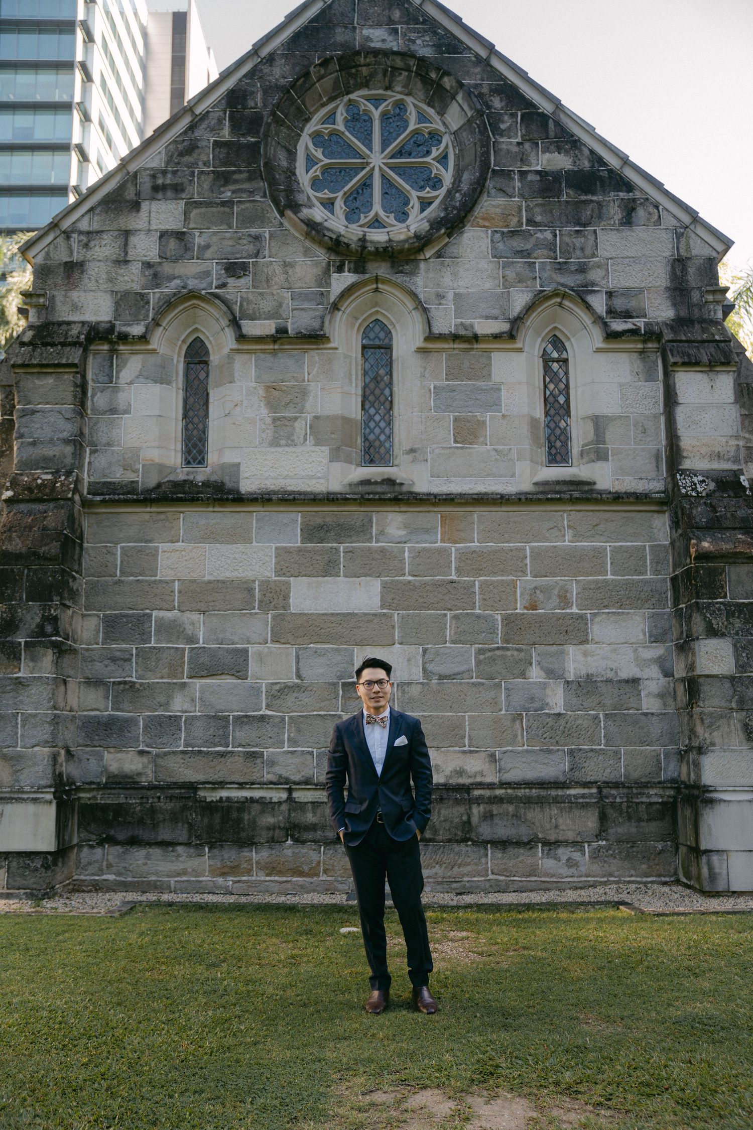 Stone church exterior with circular rose window and gothic arched windows on a sunny day.