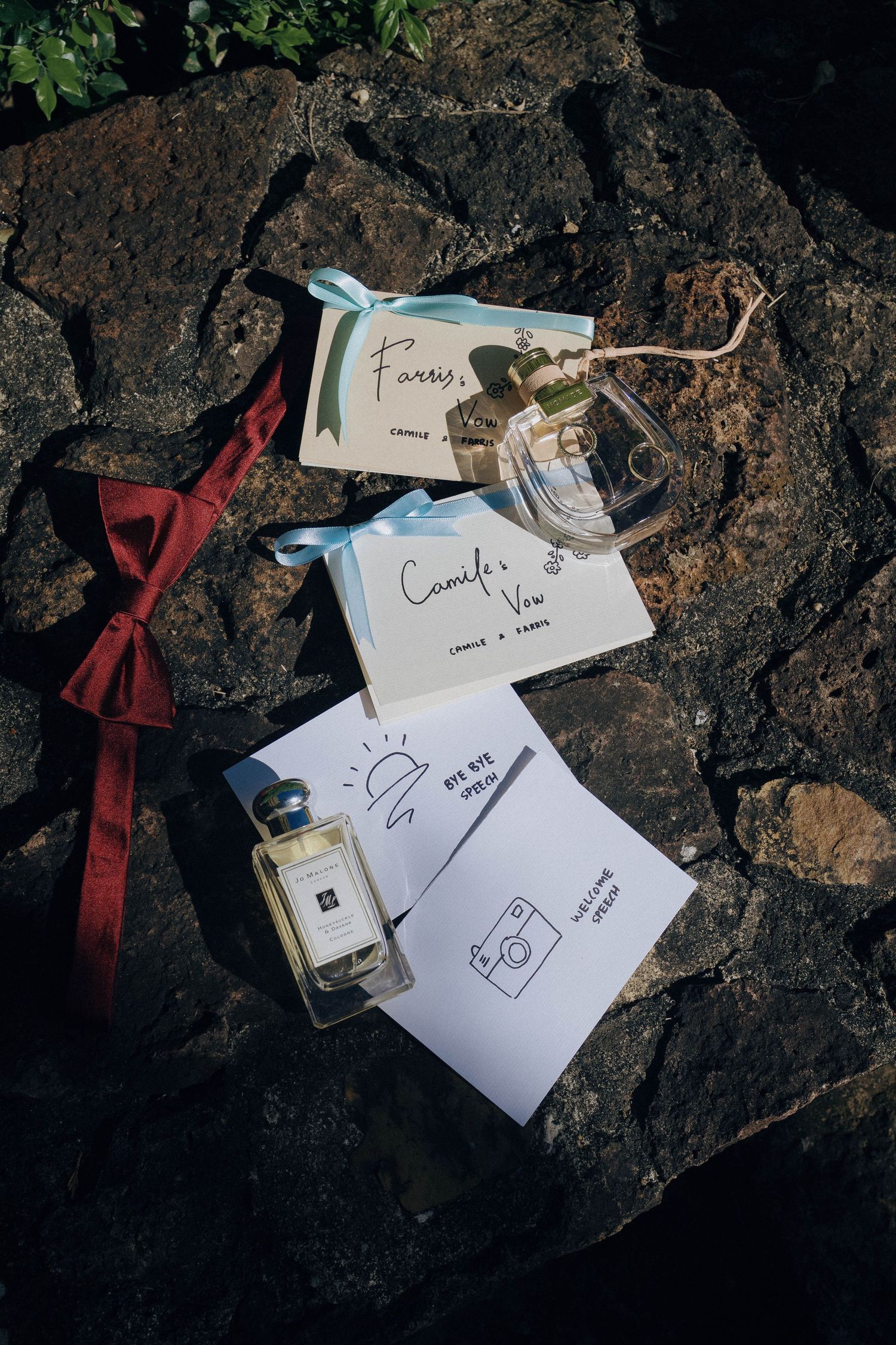 Handwritten notes and tags scattered on dark stone surface with red ribbon in moody lighting.