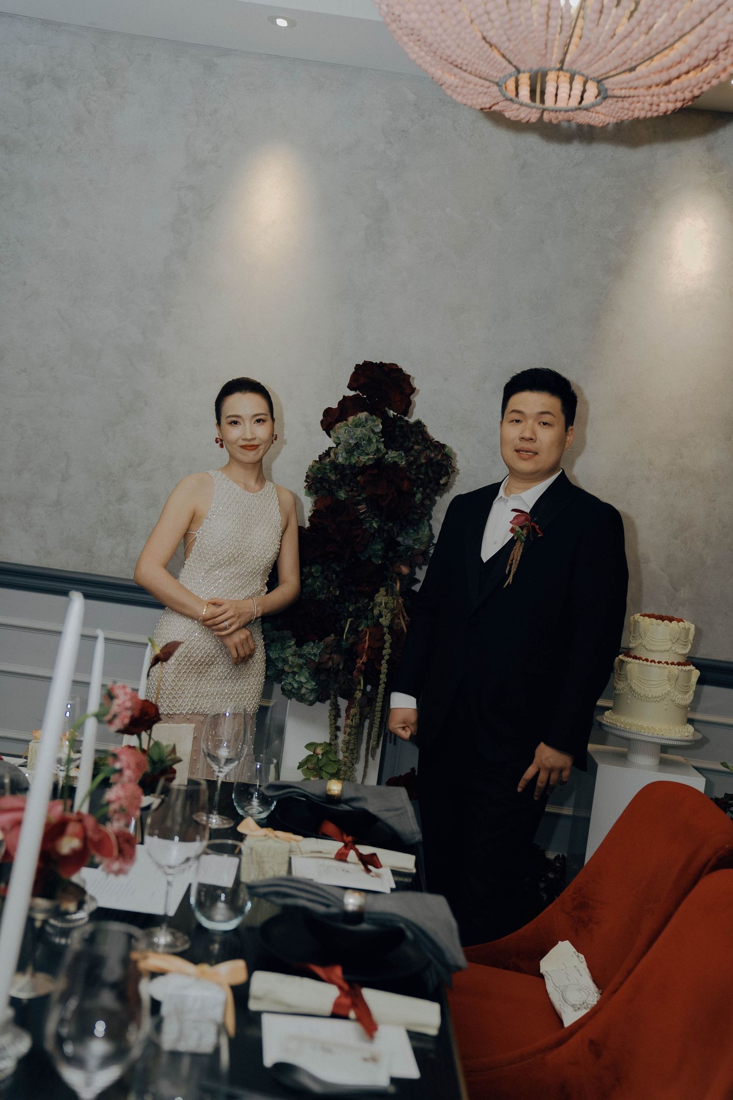 A series of wedding reception photos showing a couple cutting their cake at an elegant venue with red chairs and chandeliers.