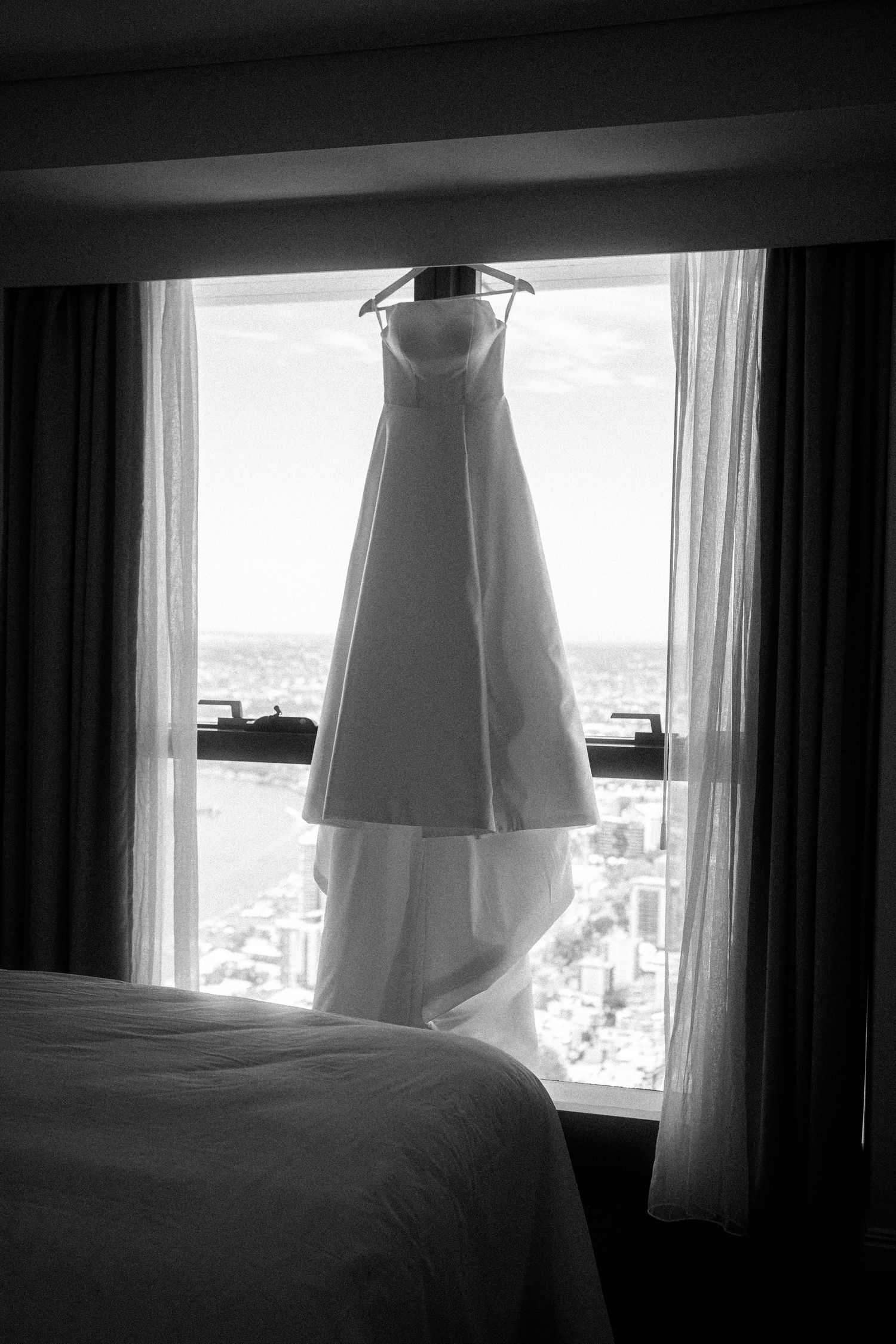 A white dress hangs in silhouette against a bright window in a series of black and white photographs.