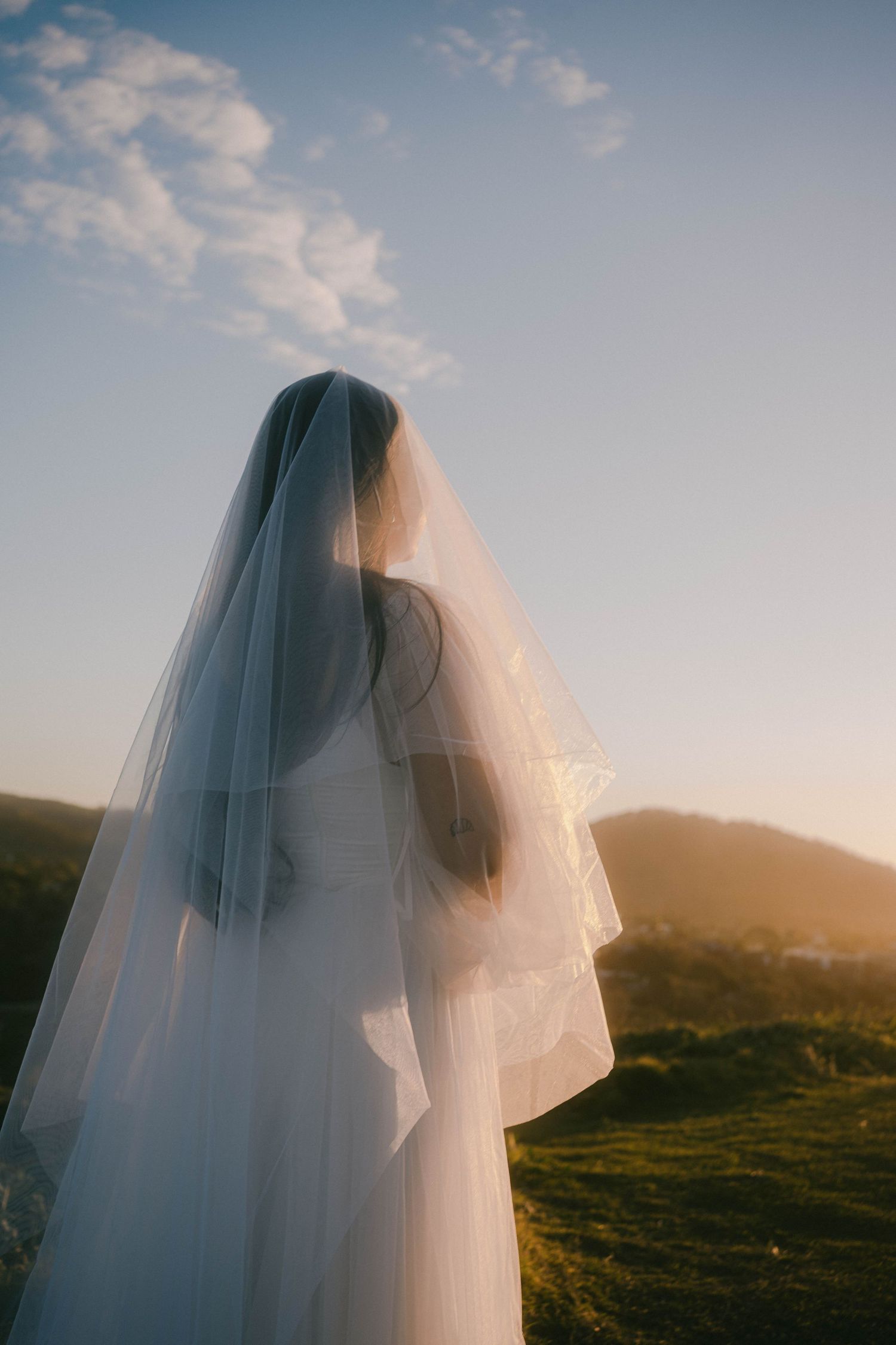 A sequence of ethereal photos showing a flowing white wedding veil billowing in the wind against a sunset mountain landscape.