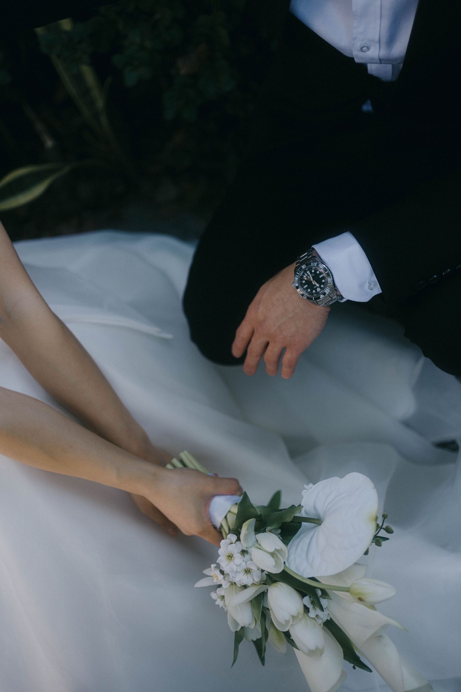 Close-up view of hands arranging delicate white floral decorations on a light fabric surface.