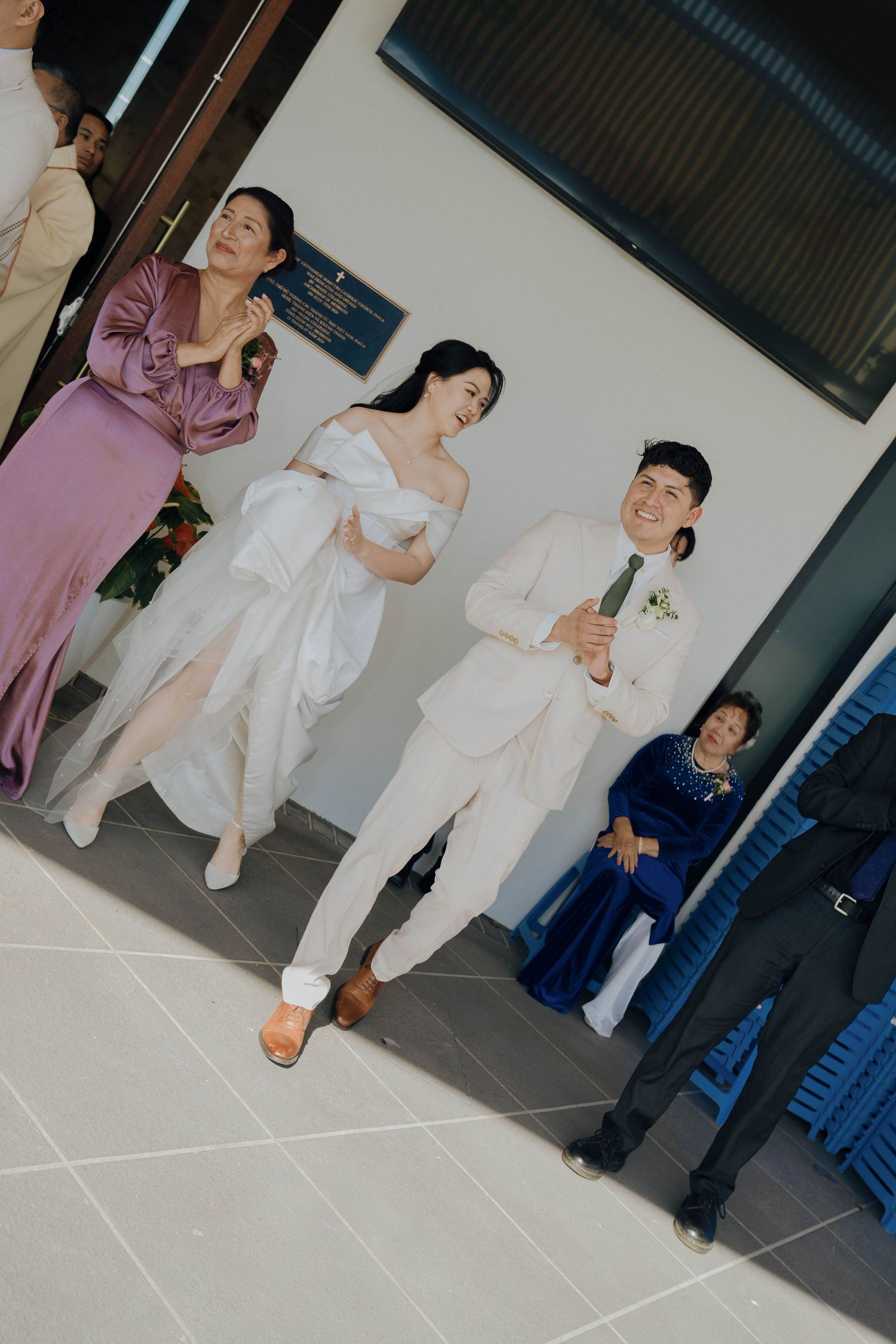 Wedding party in coordinated formal attire including purple, white and navy outfits pose together in an indoor setting.