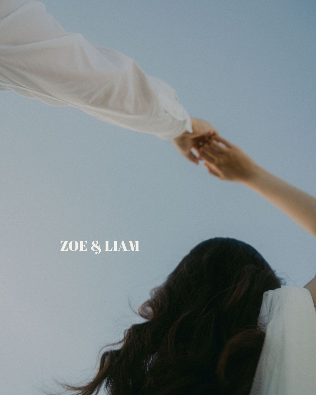 A hand reaches up to hold a flowing white veil against a blue sky with text reading 'ZOE & LIAM' at bottom.