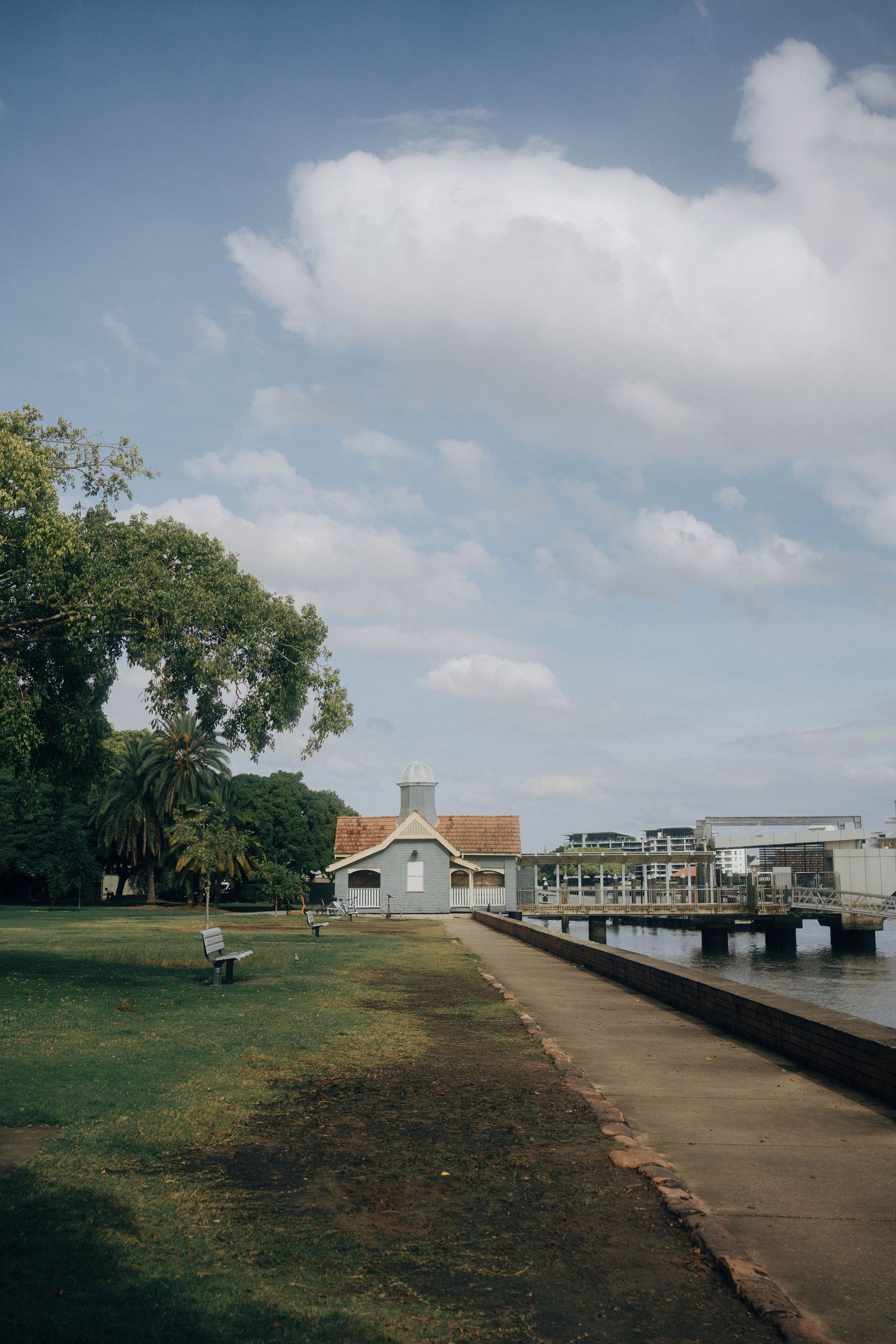A series of coastal dock walkways and buildings along a waterfront under partly cloudy skies.