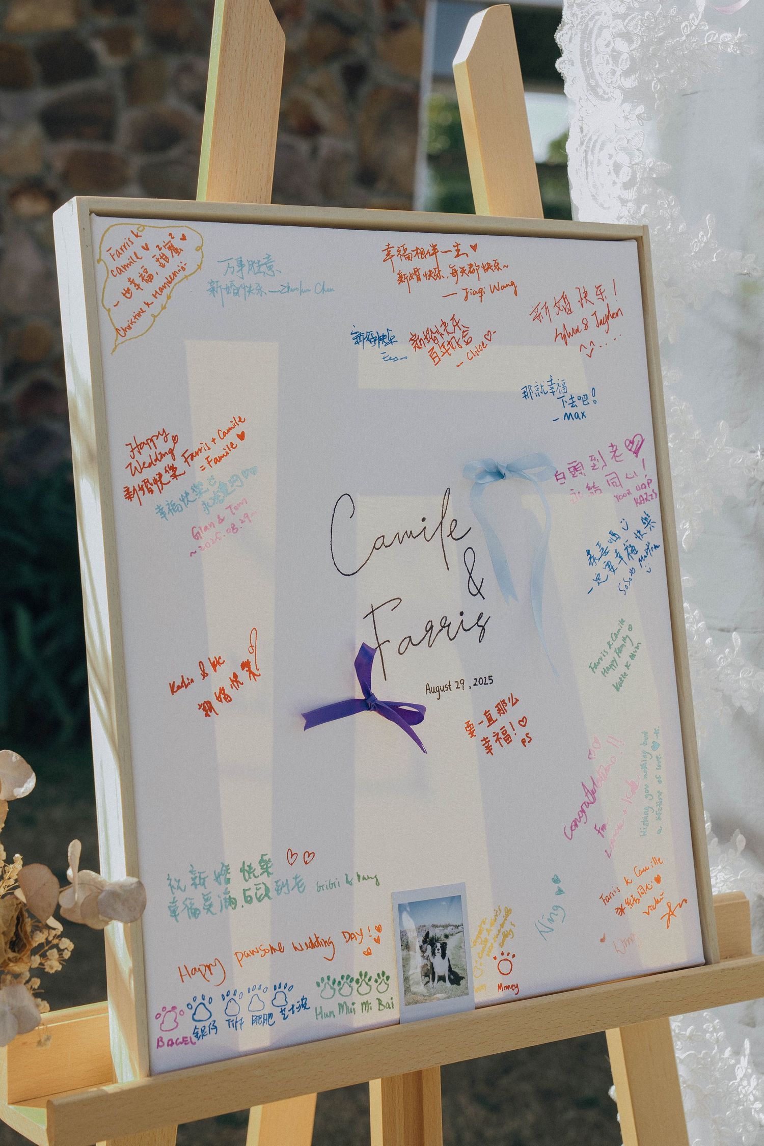 White message board with colorful handwritten notes and signatures displayed on a wooden easel.