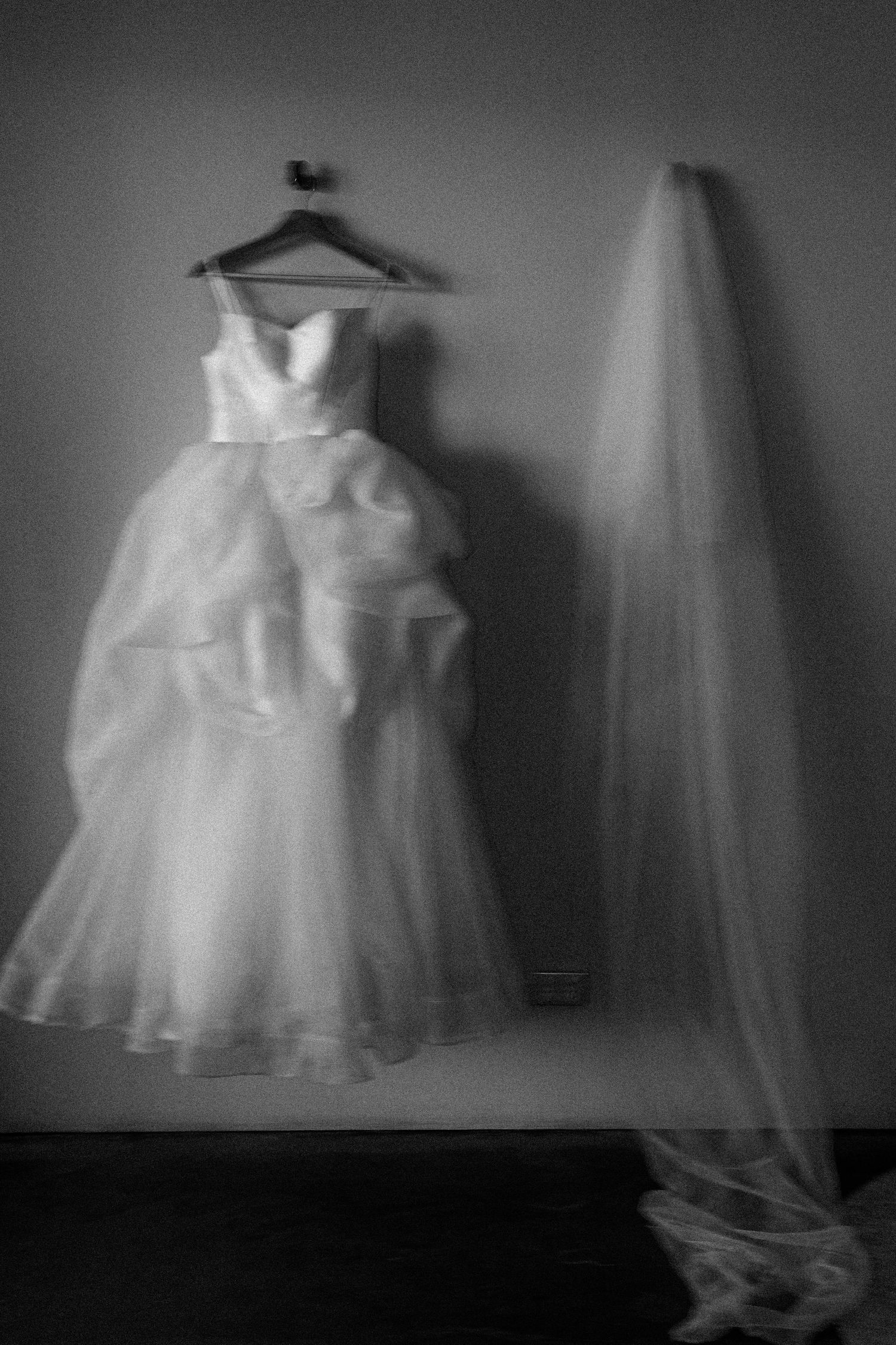 A series of ethereal black and white photographs showing wedding dresses on hangers in a dark moody setting.