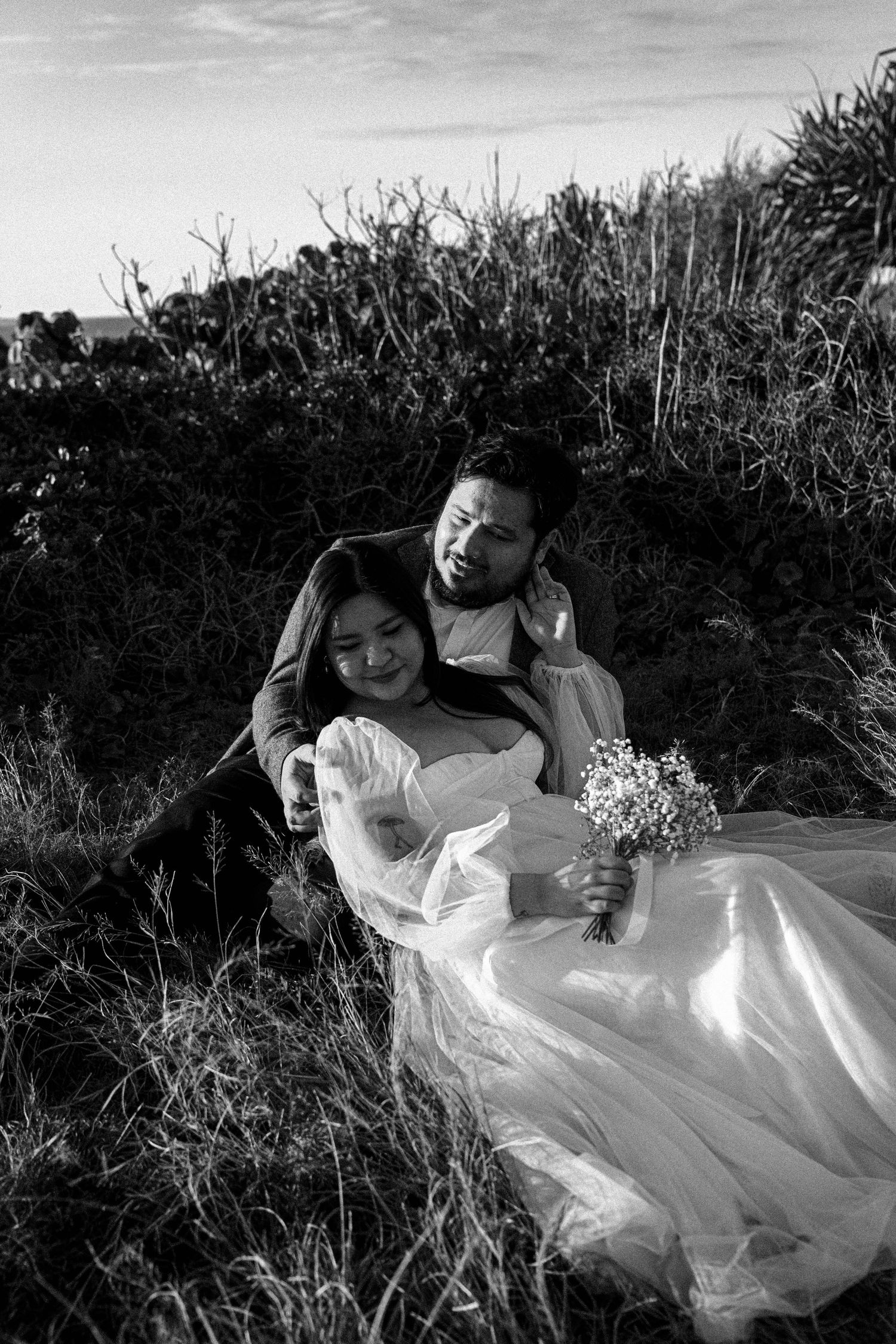 A series of black and white photographs showing a person in a flowing white dress laying in tall grass.