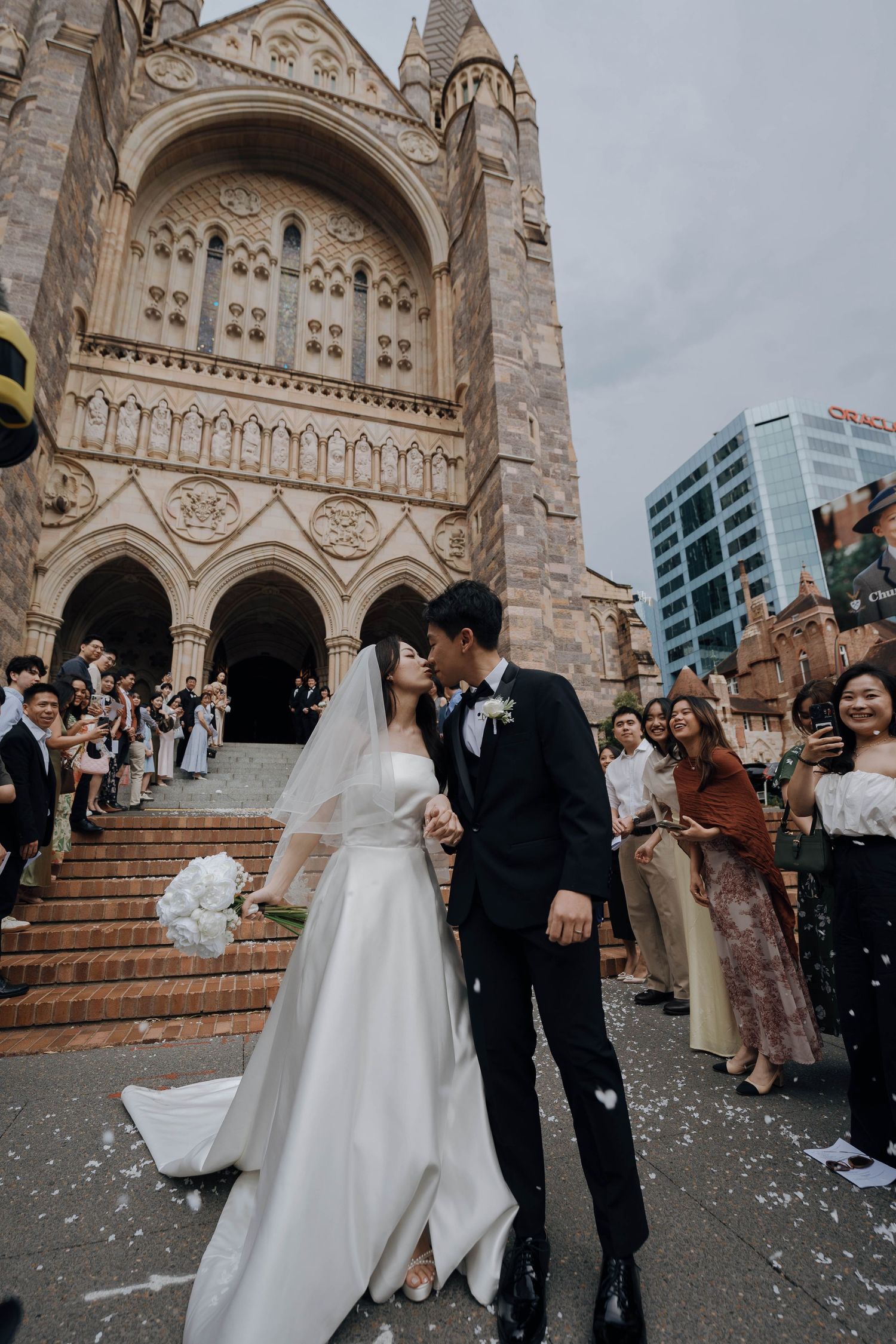 Wedding celebration on church steps with confetti being thrown as couple exits historic cathedral building.