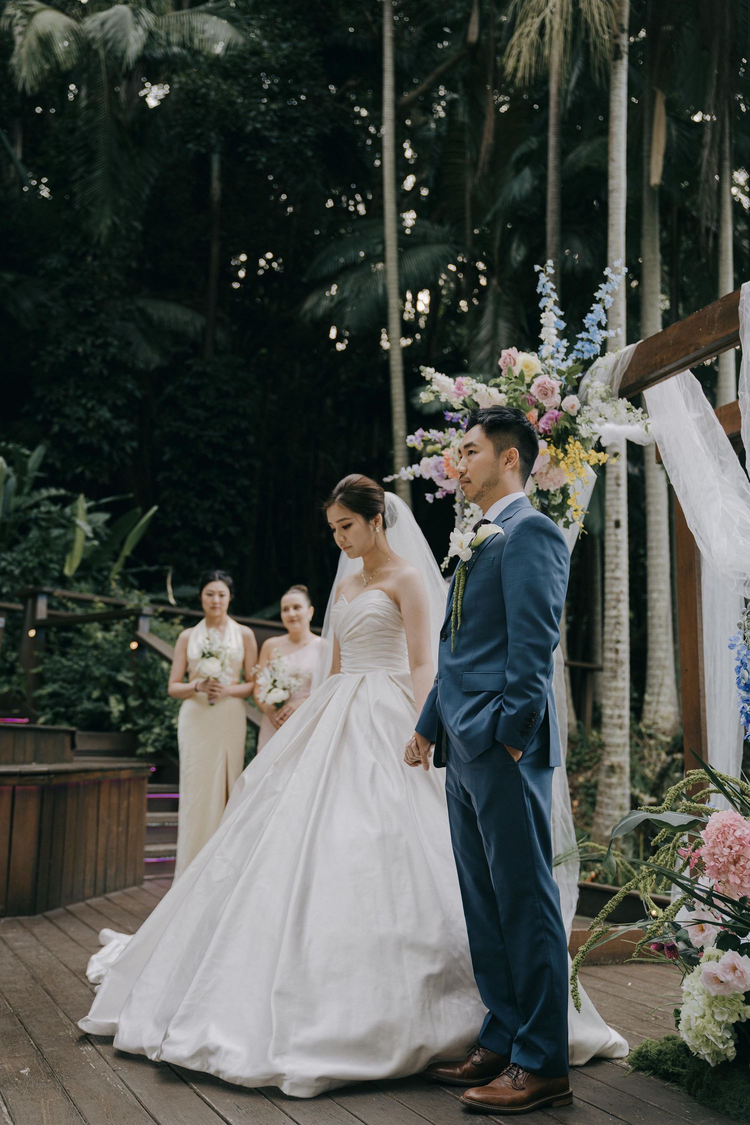 Wedding party members share a lighthearted moment together during an outdoor garden ceremony.