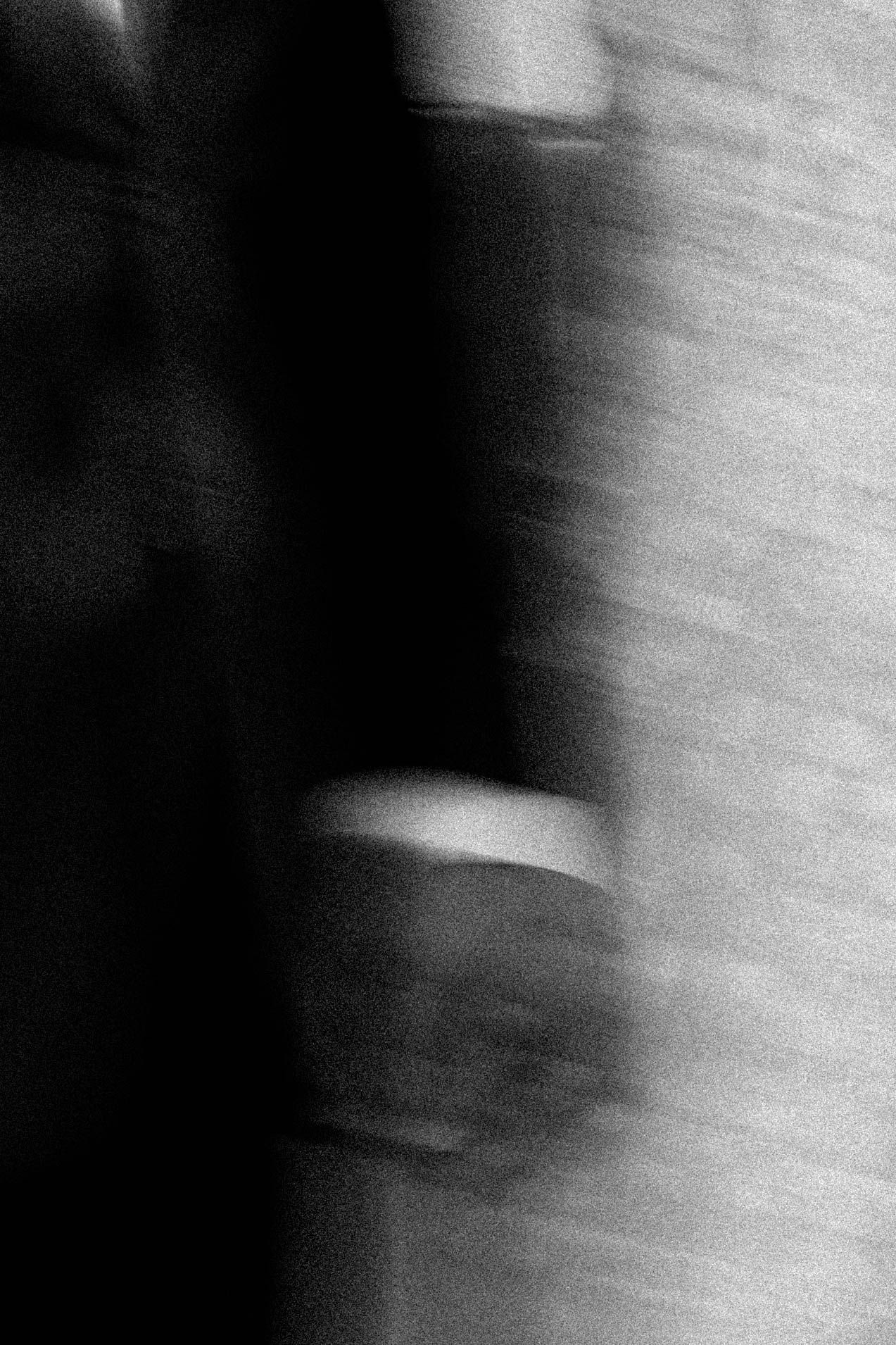 Abstract black and white photograph showing blurred movement with dark shadows and light streaks against a white wall.