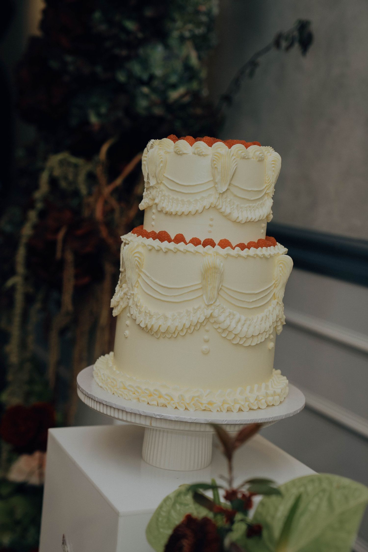 A series of elegant white wedding cakes with delicate piped designs displayed on cake stands at an outdoor reception.