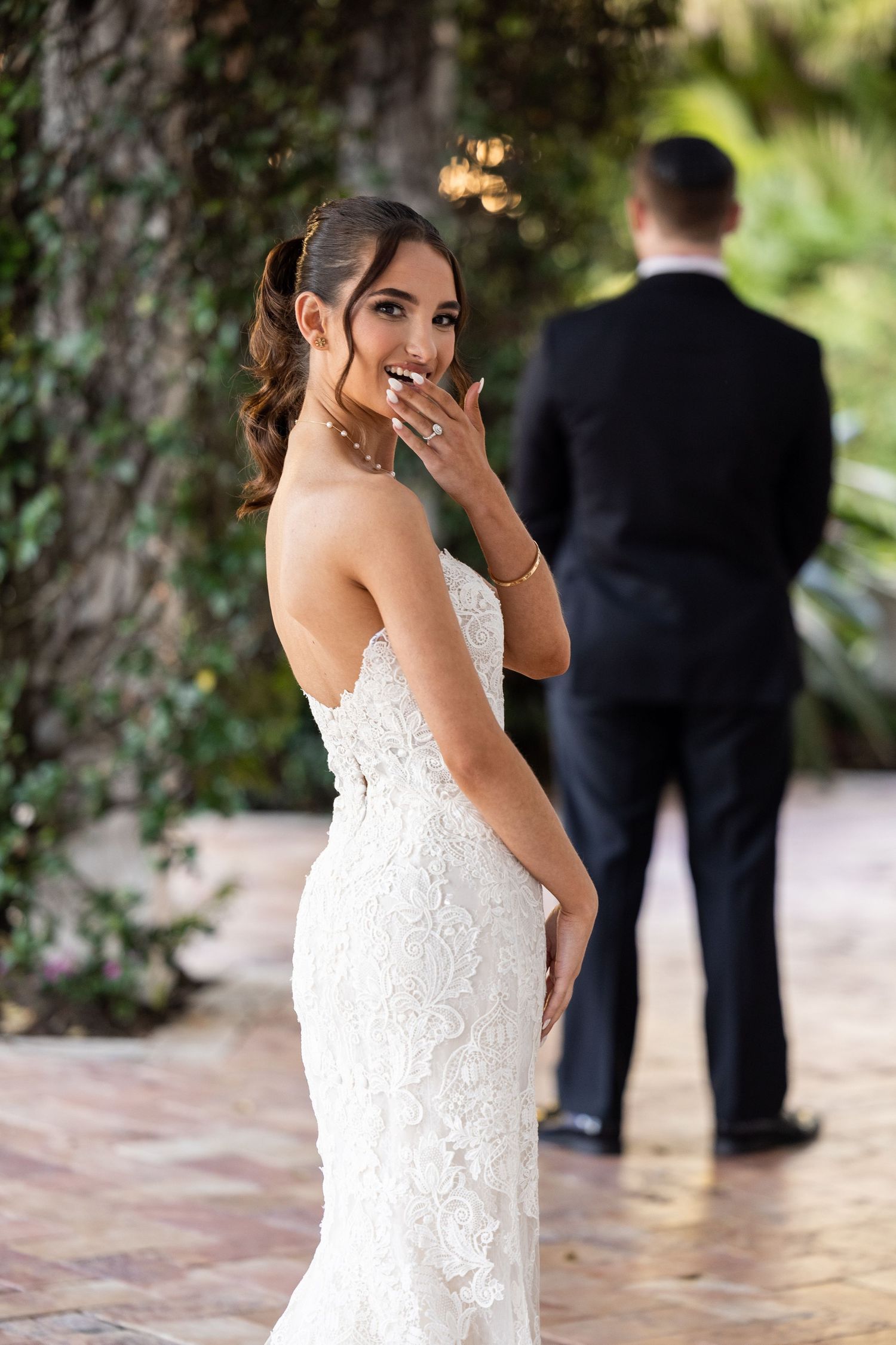 A joyful moment captured in a lace wedding gown against a garden backdrop.
